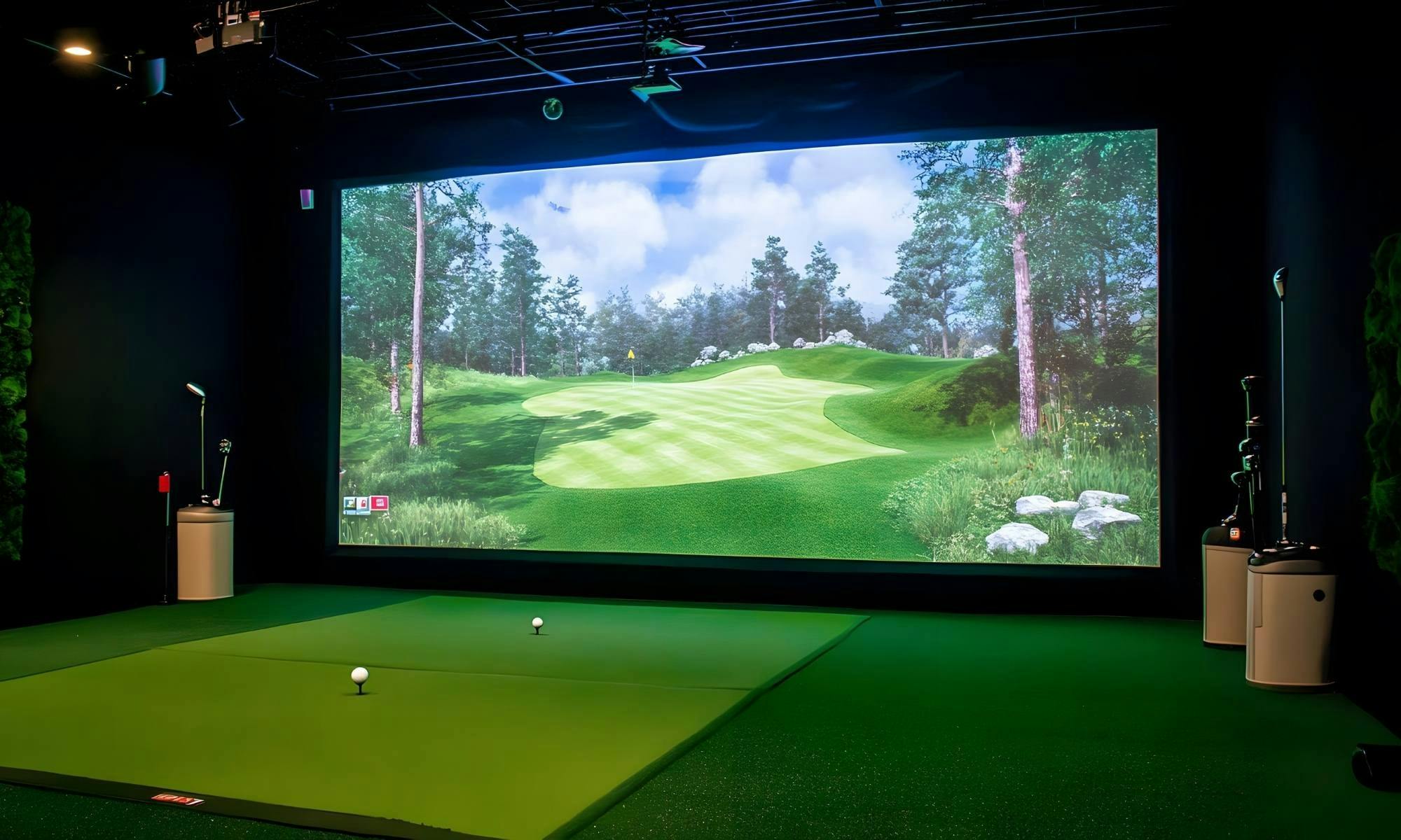 Indoor golf simulator room with large screen, green mat, and ambient lighting.