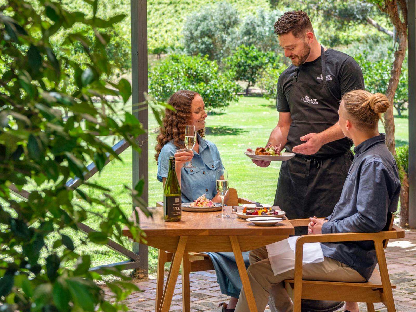 Head Chef Wayne Leeson delivering food to the guests table, and introducing their dish.