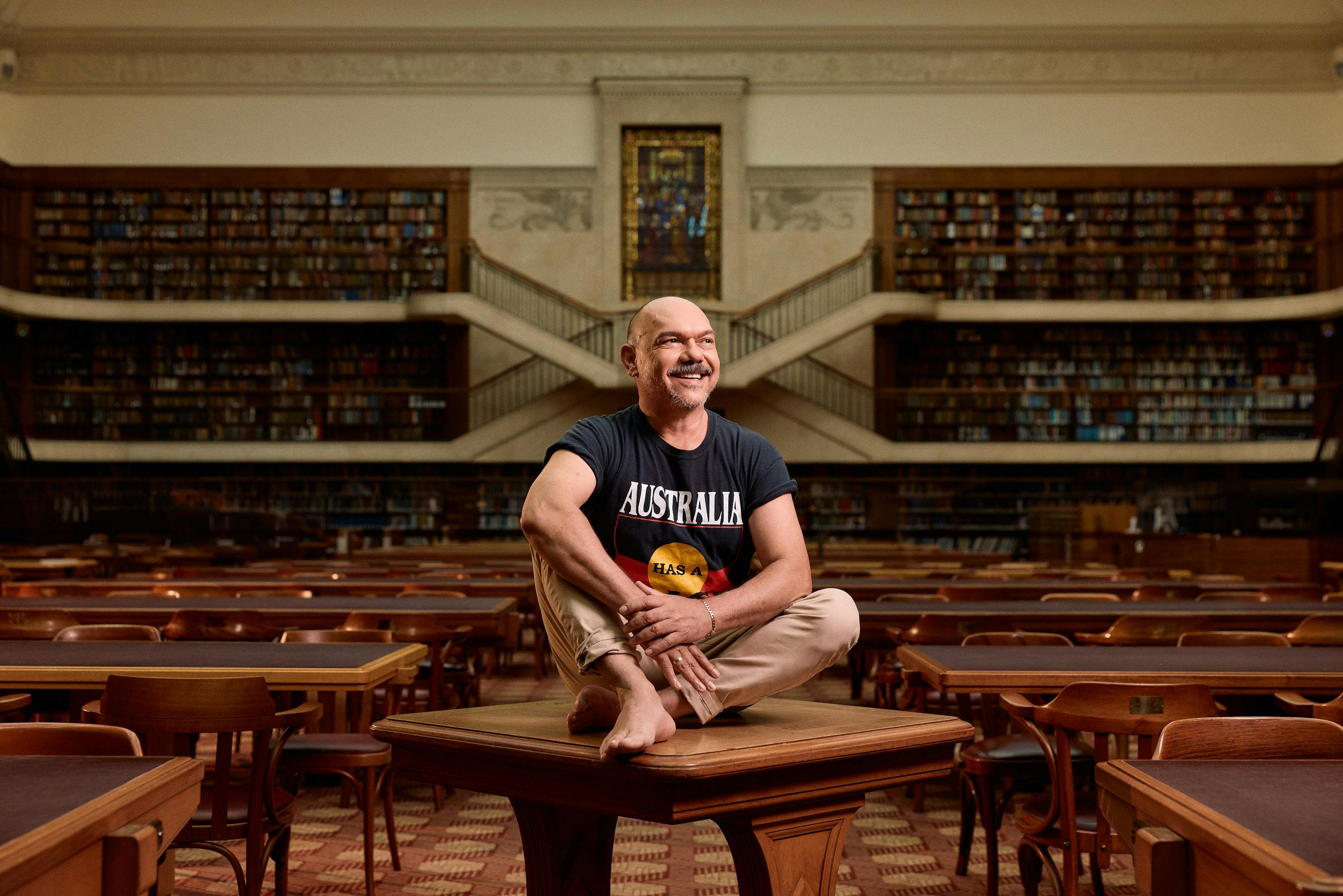 A man sitting on a table in a library reading room