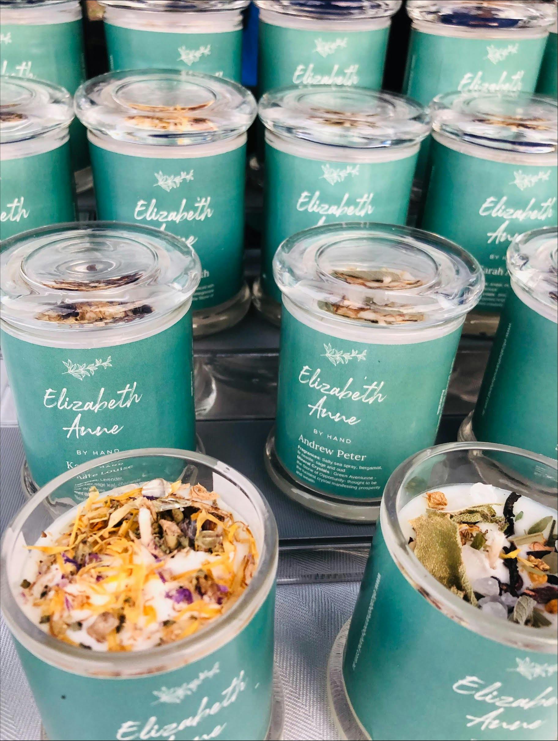 Candle jars with blue labels reading Elizabeth Anne