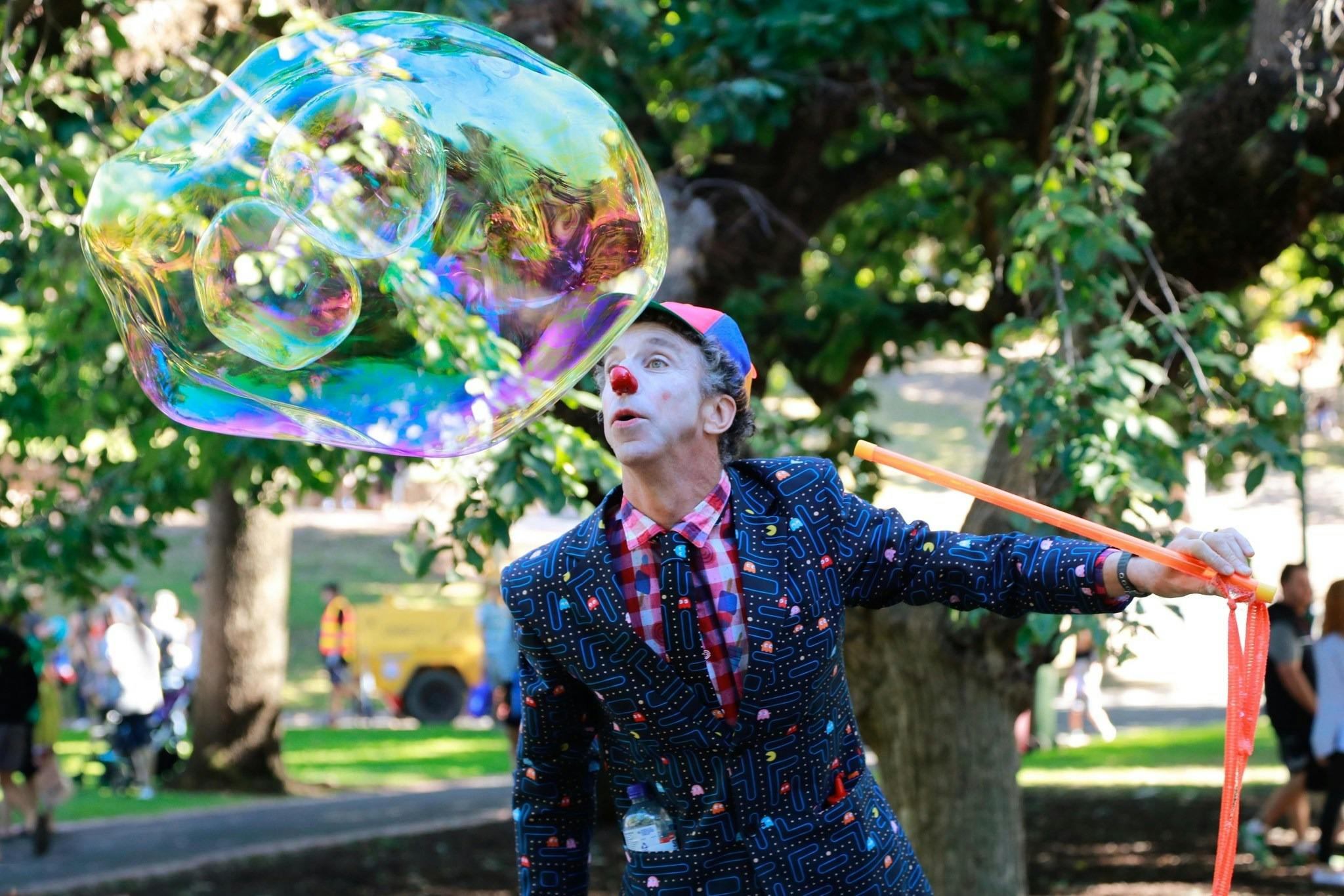 Tim Tim the entertainer with face paint is blowing a giant bubble