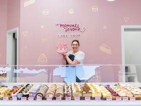 Sally holding cake in front of shop display