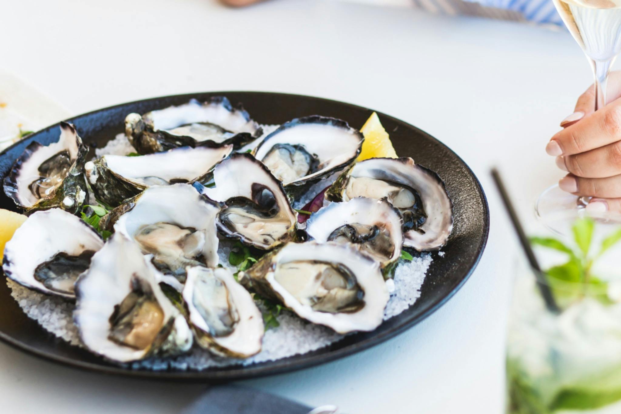 Fresh oysters on a black plate with lemon wedges