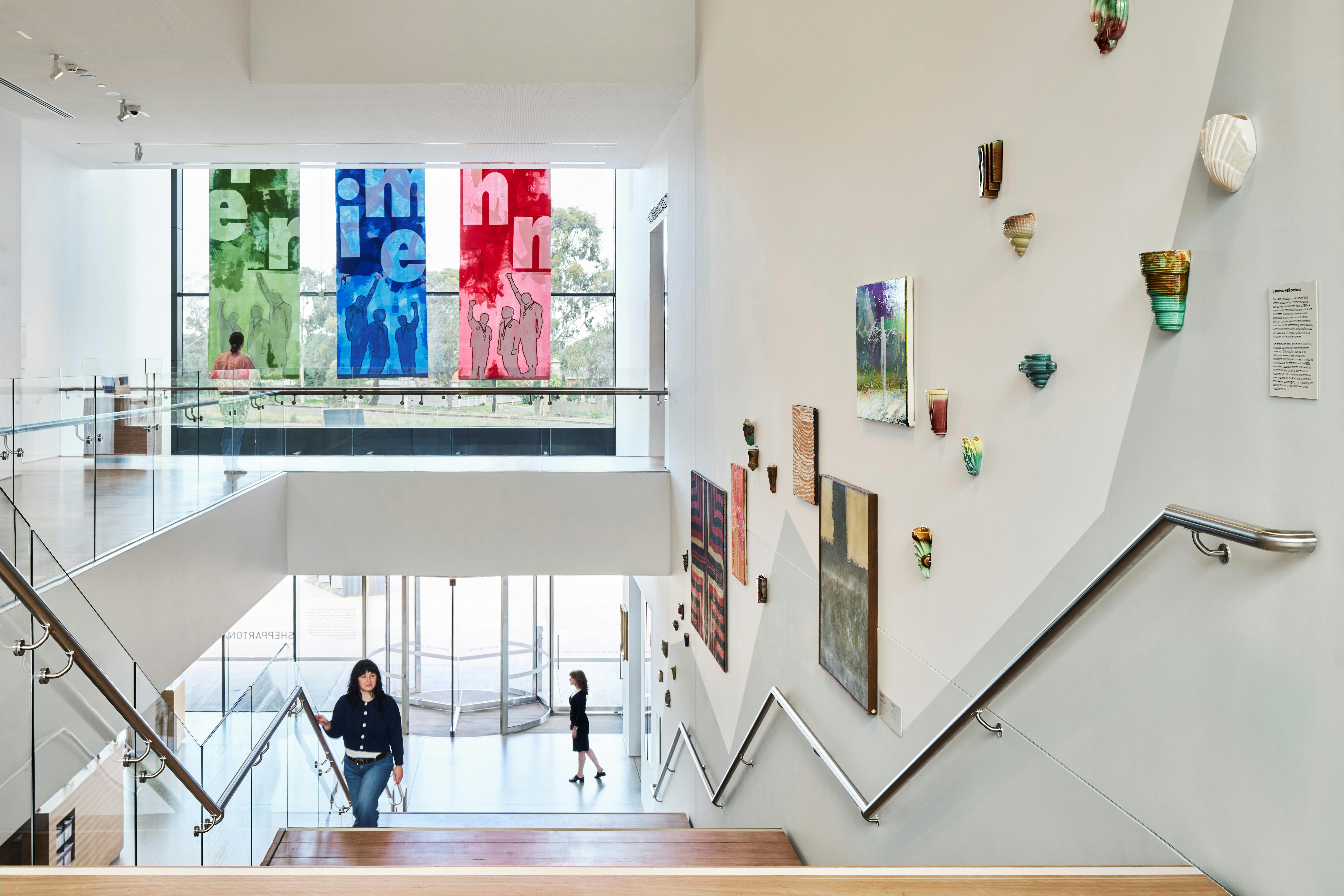 A woman climbs the staircase through the atrium of a contemporary art museum.