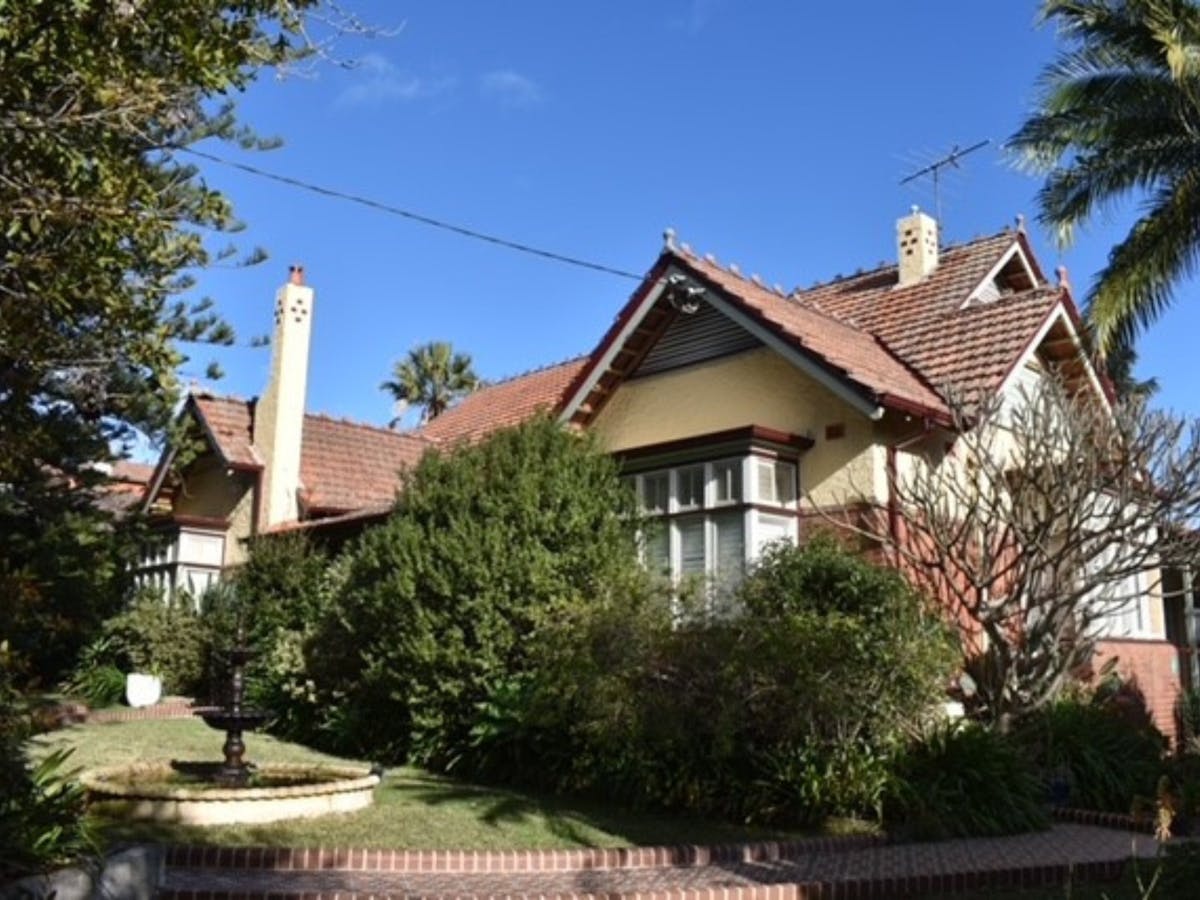 A typical house of the Federation era stands proudly against a blue sky + a palm tree and shrubbery.