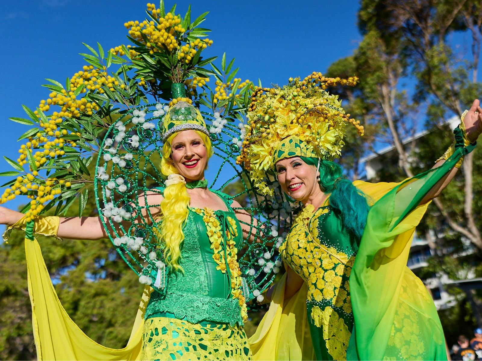 Two entertainers standing outdoors dressed in green and gold