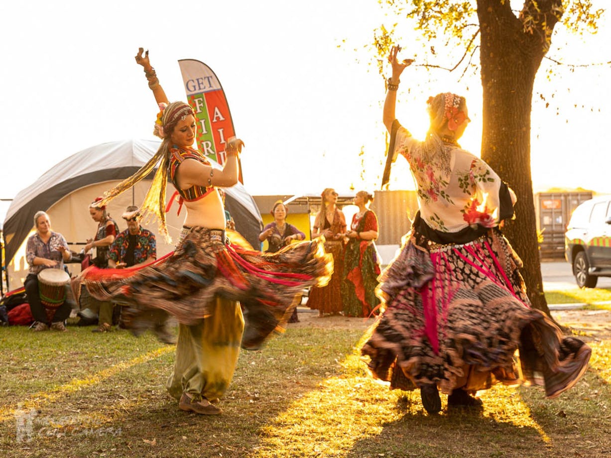 2 woman dressed in traditional Turkish dresses dance for a crowd