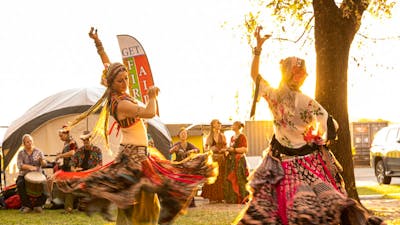 2 woman dressed in traditional Turkish dresses dance for a crowd