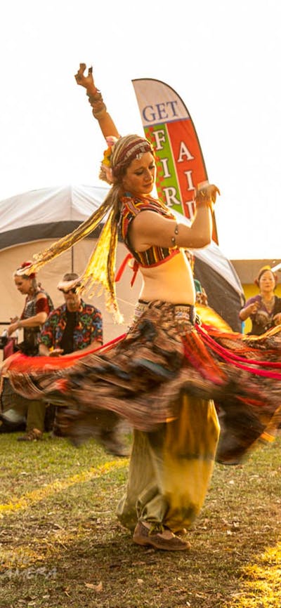 2 woman dressed in traditional Turkish dresses dance for a crowd