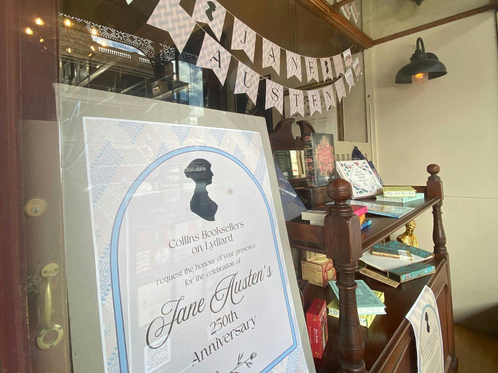 A window display of Jane Austen products, focusing on an invitation for customers to celebrate.