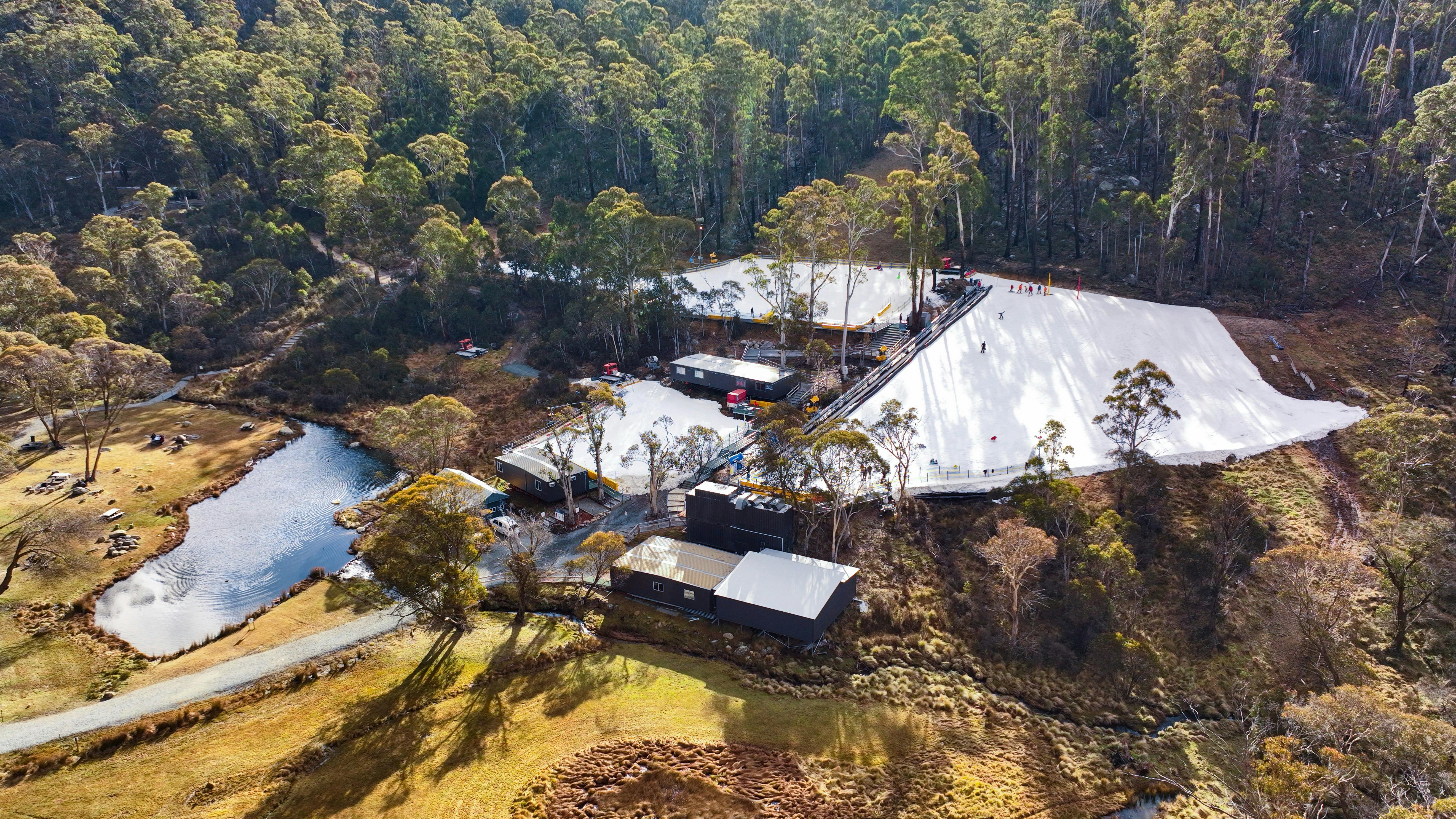 Corin Forest as seen by a drone. There are 3 large patches of snow & a small dam surrounded by trees