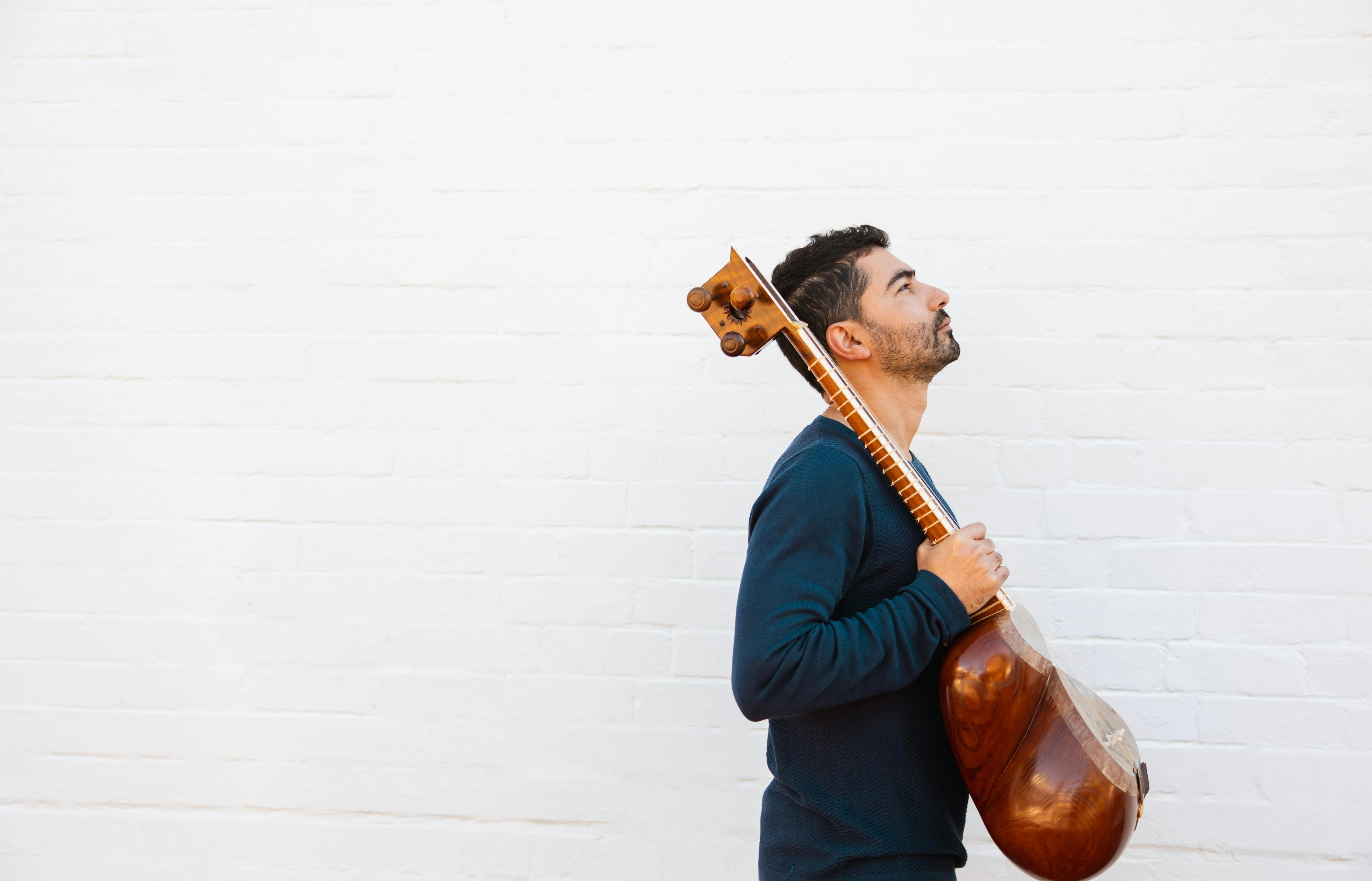A person in a blue jumper holding an instrument and looking up