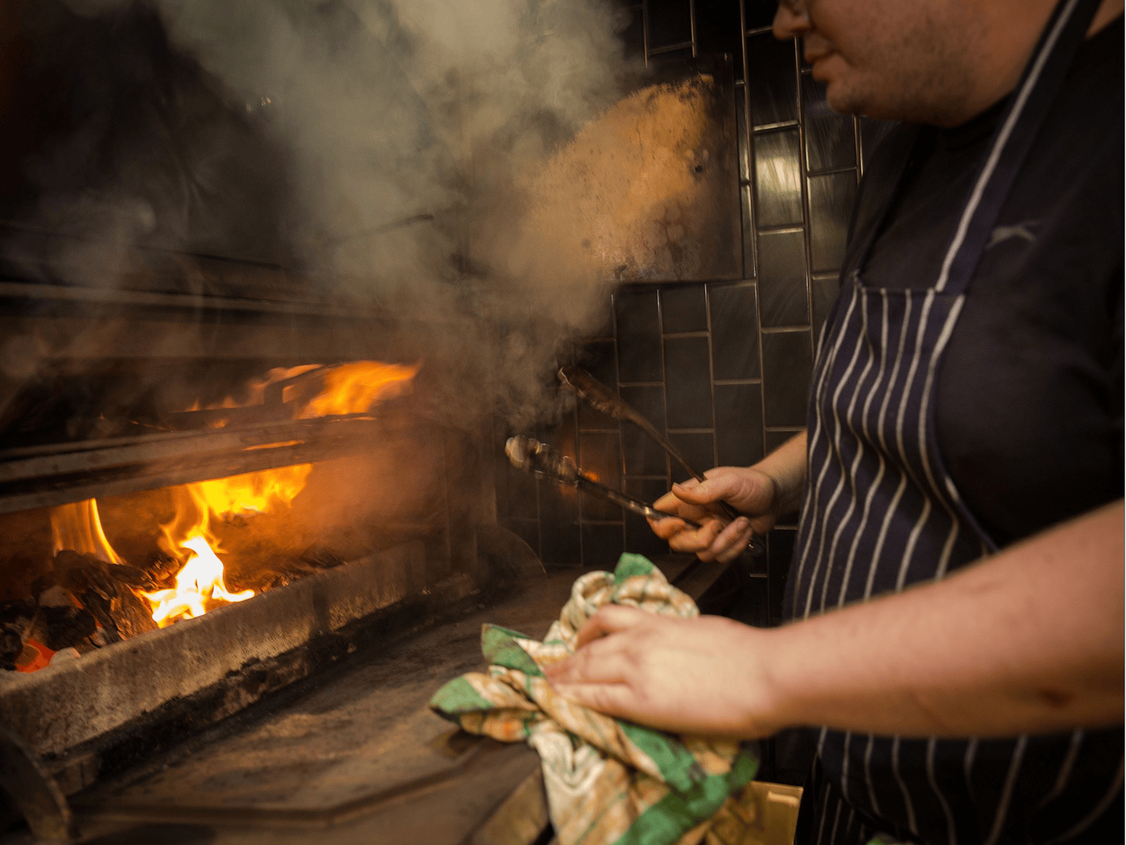 Chef in front of an open fire grill
