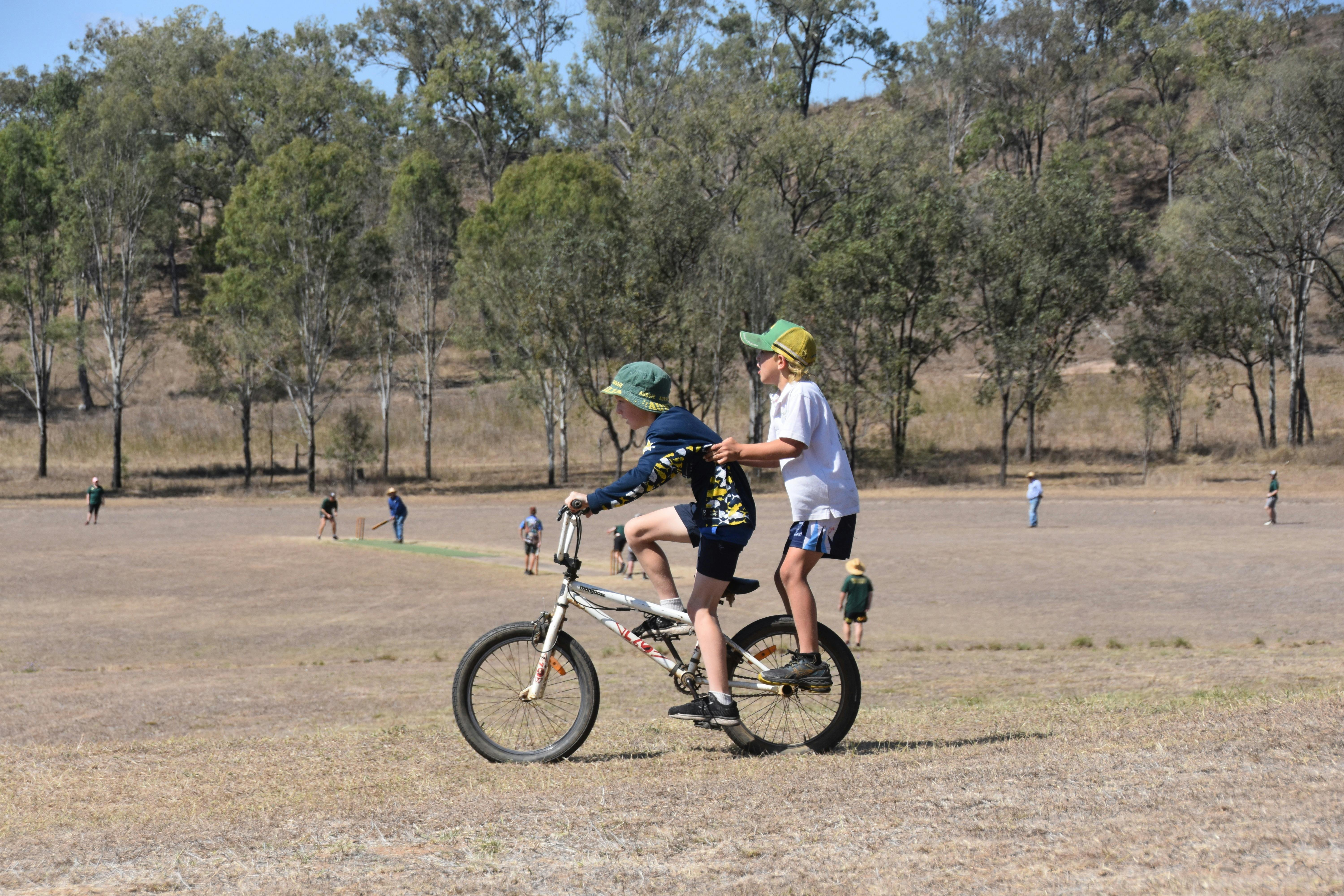 Children riding bike around cricket pitch