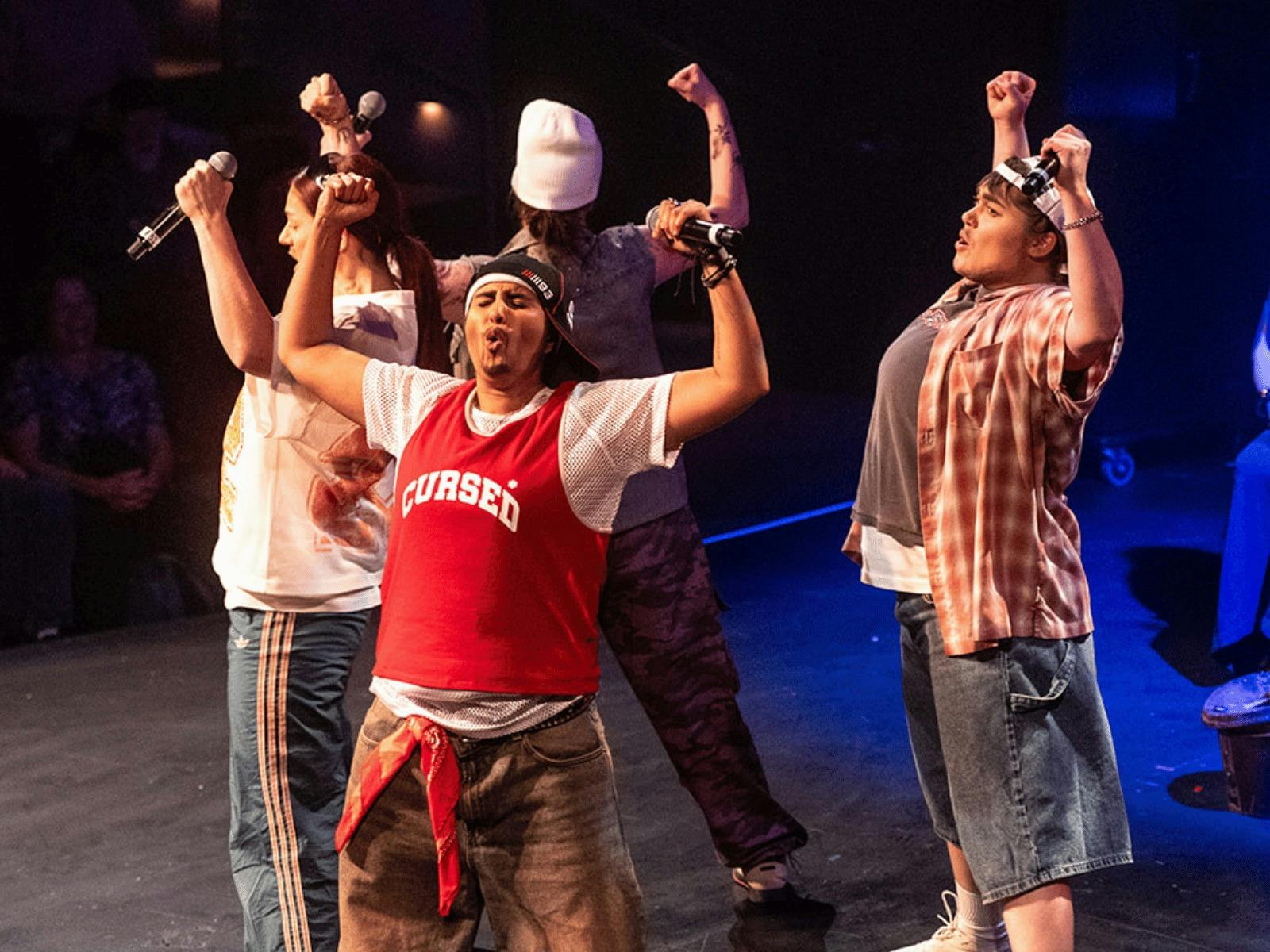 Four Drag Kings dressed as boy band members performing on stage