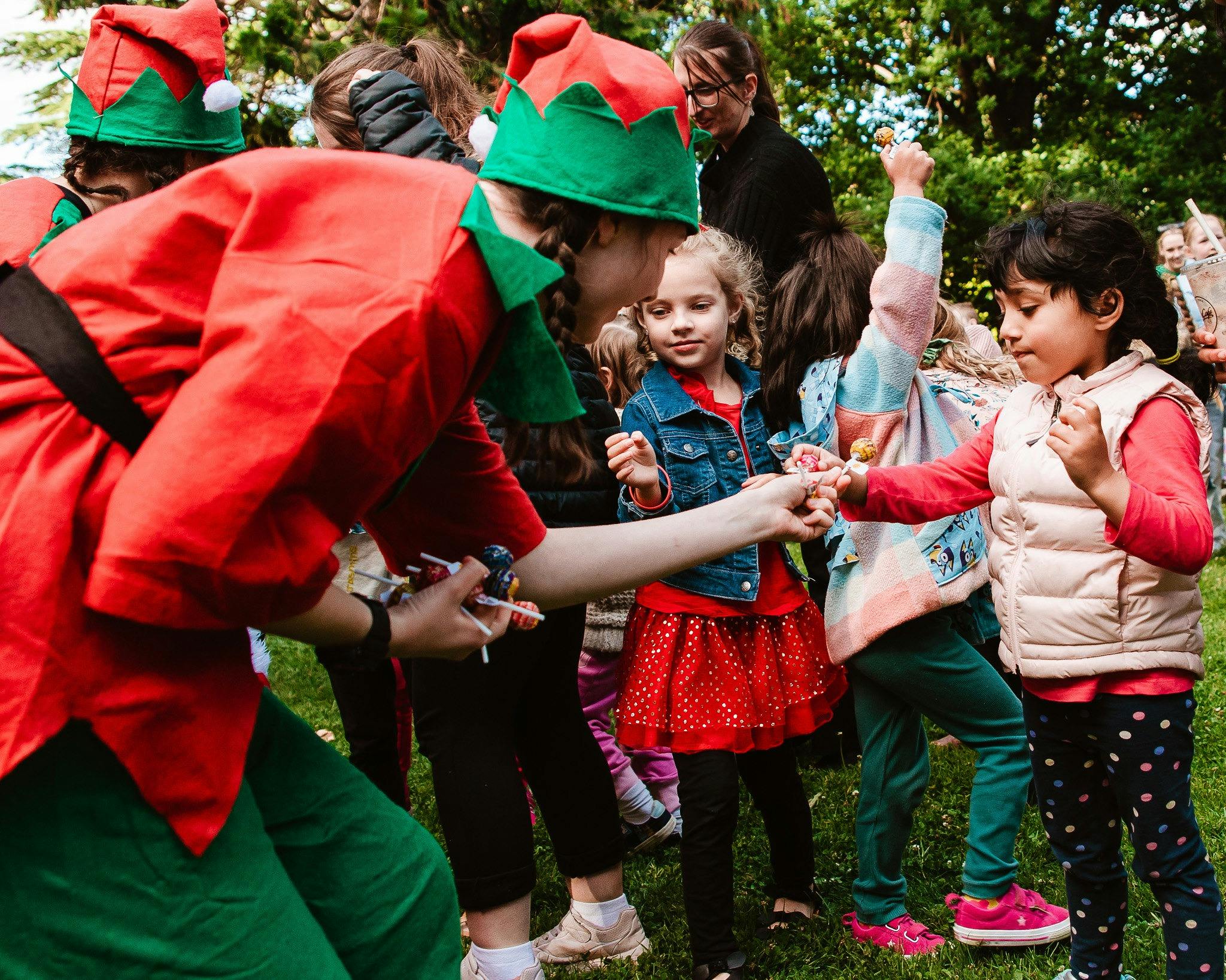 Young people dressed as Santa's elves interacting with children