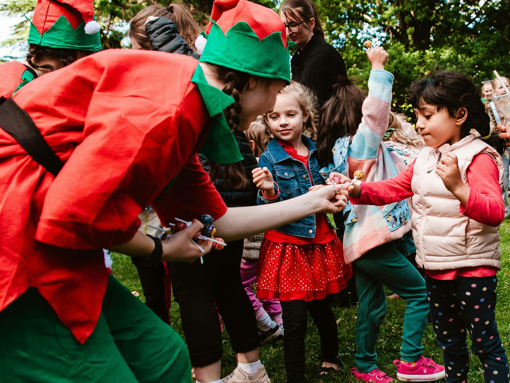 Young people dressed as Santa's elves interacting with children