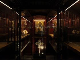 Liturgical artefacts displayed inside an old vault, which is dark red and atmospheric