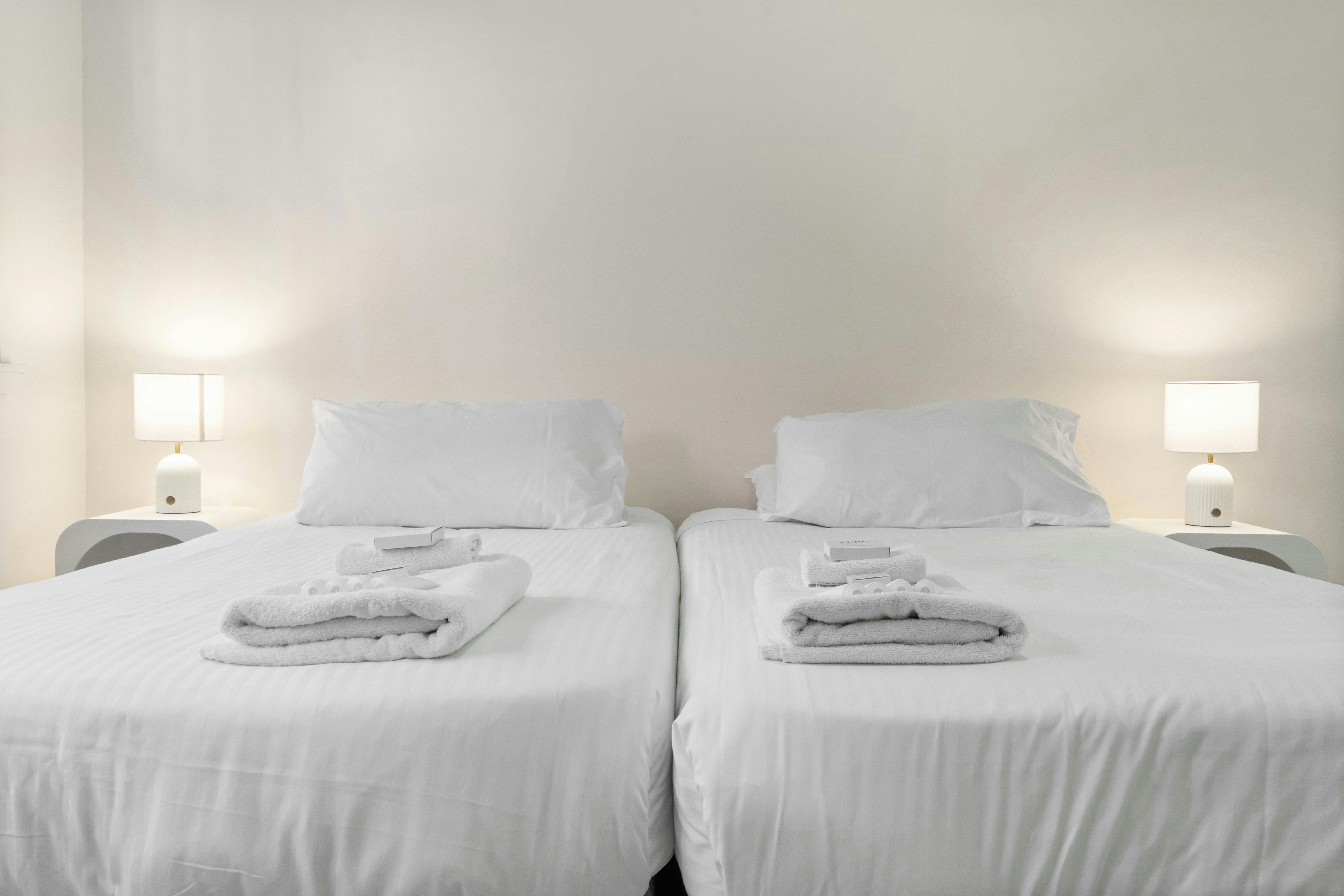 雙人床配有乾淨的毛巾和簡約的床頭燈。