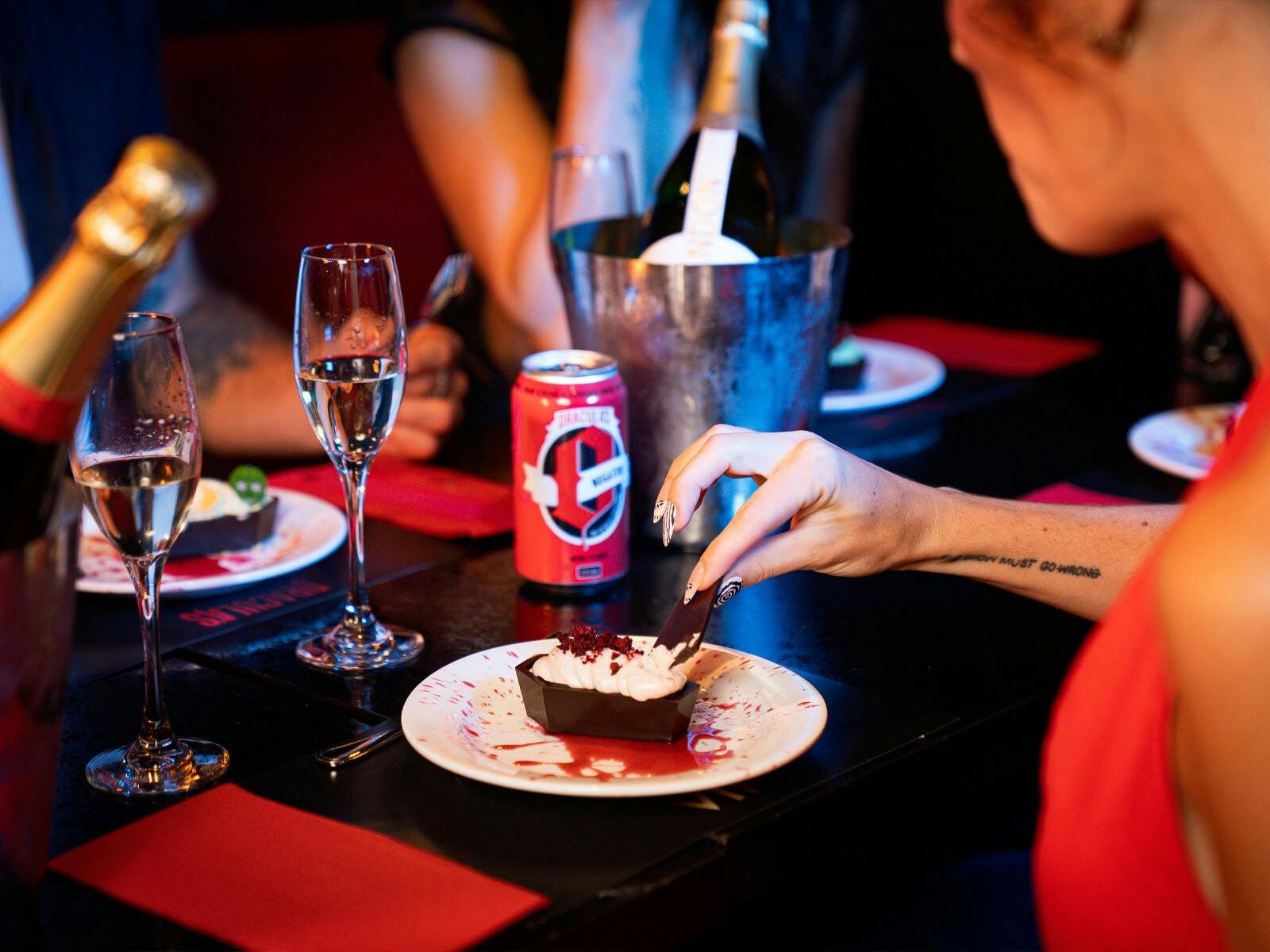 Guests enjoying Dracula's signature coffin dessert with drinking sparkling wine at their table.