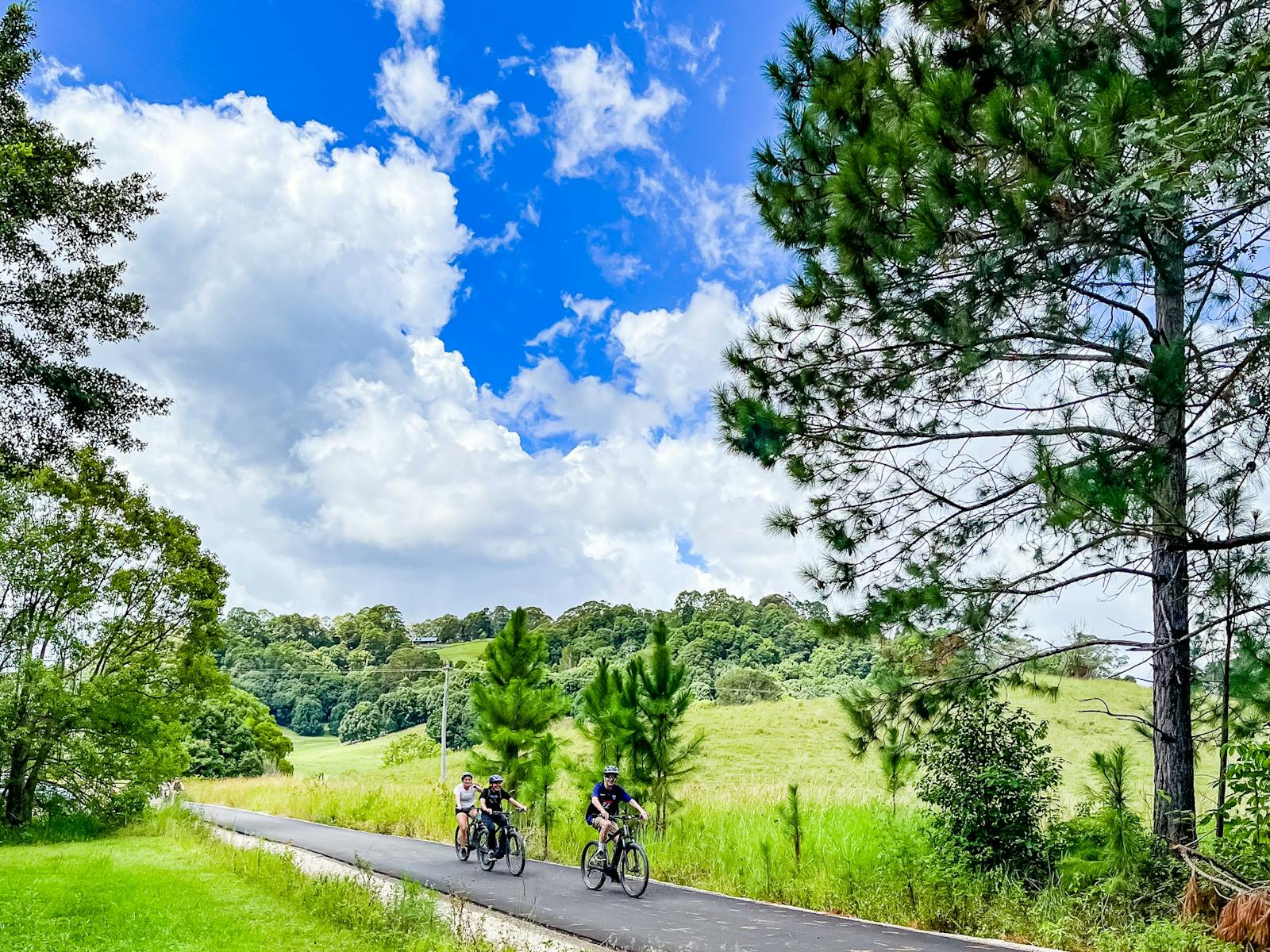 Three E Bike riders approaching viewer in nature at Stokers Siding on the Northern Rivers Rail Trail