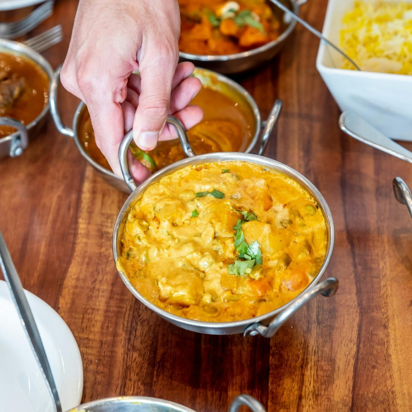Hand lifting up a Korma curry