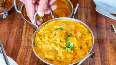 Hand lifting up a Korma curry