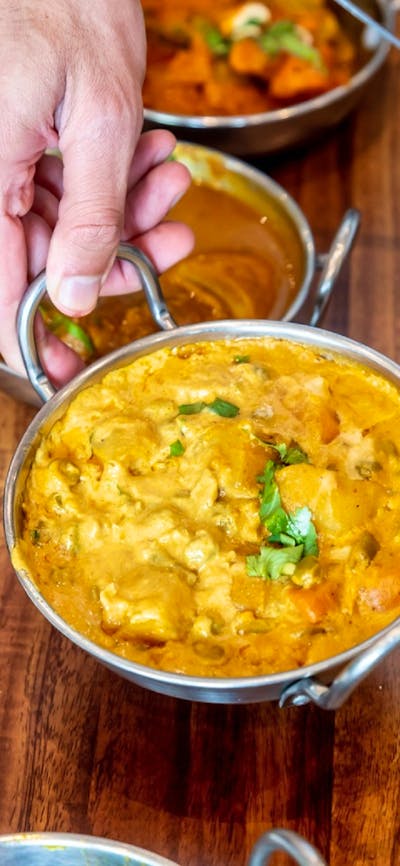 Hand lifting up a Korma curry