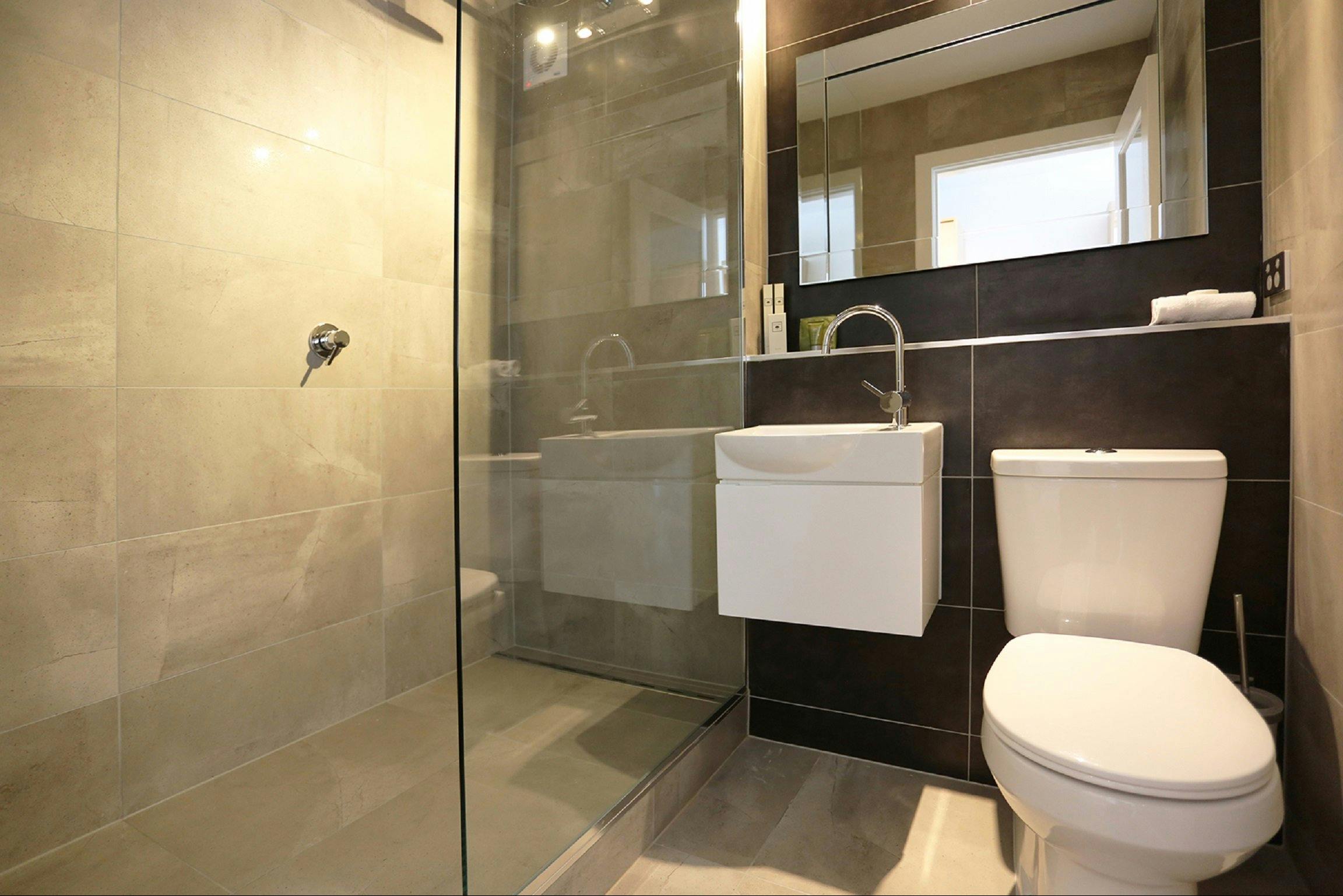 Hotel bathroom showing toilet, hand basin and walkin shower.
