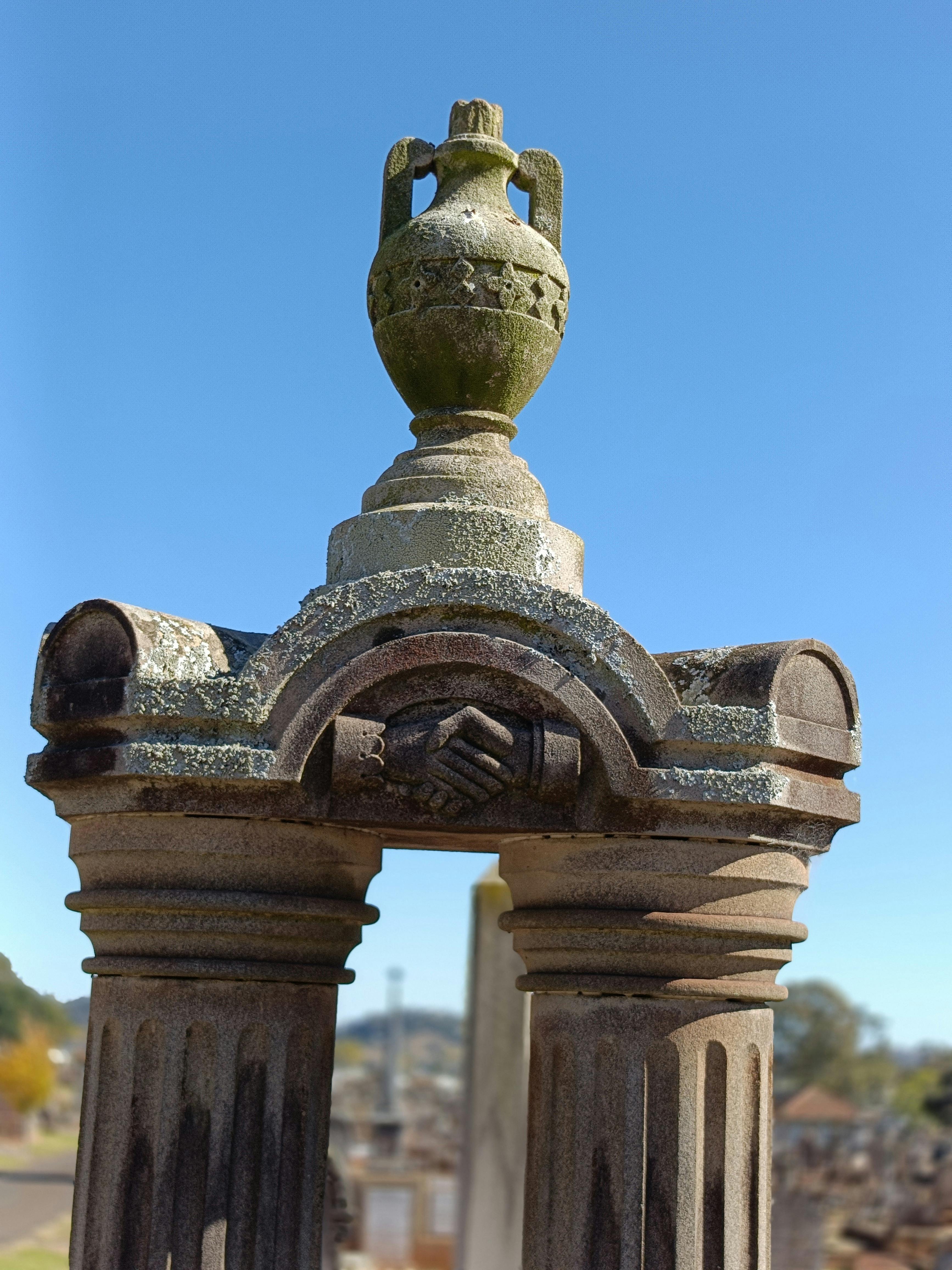 Two clasped hands, etched in sandstone. The left cuff is frilled and feminine, the right is manly.