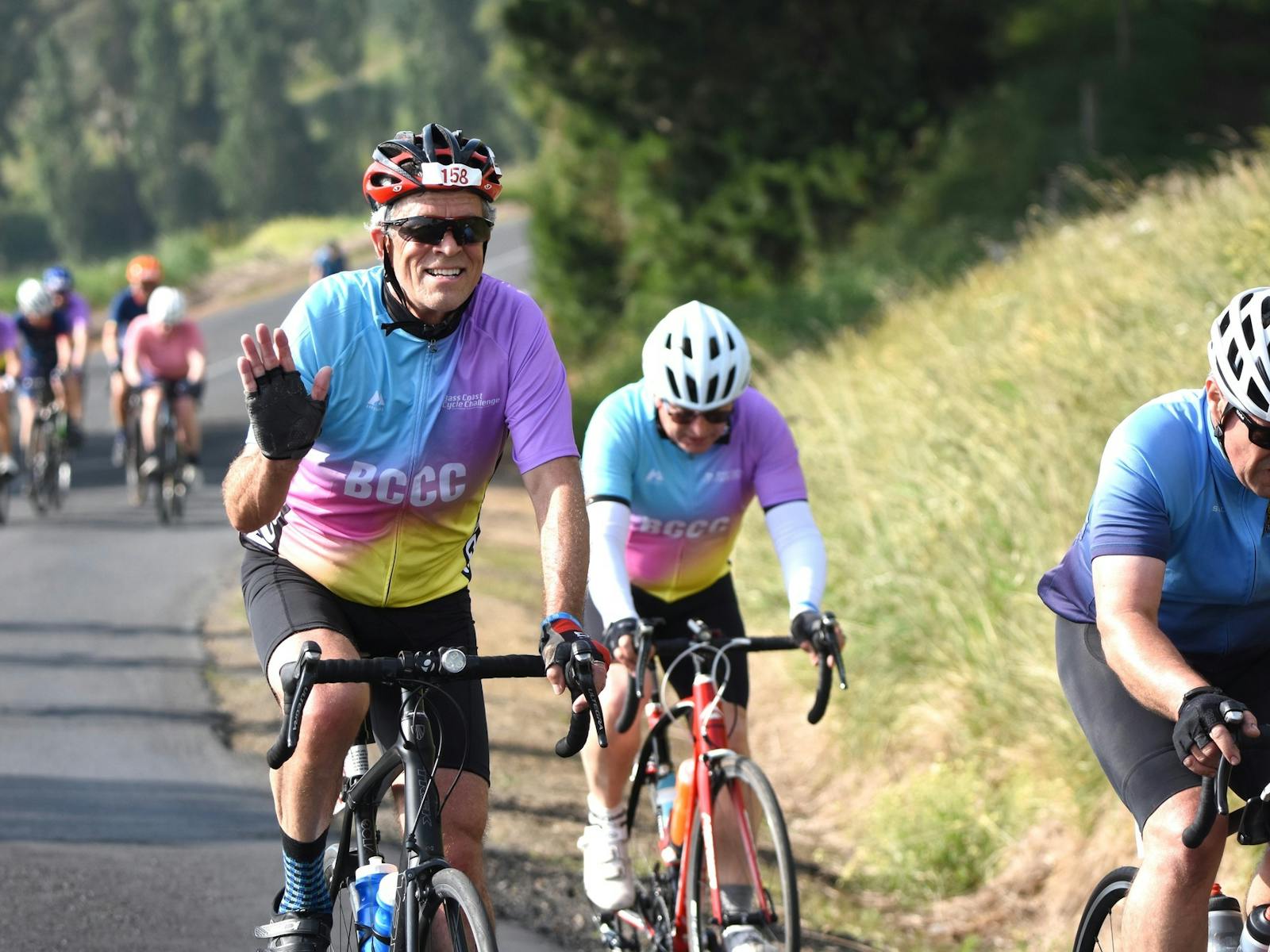 Rider in bright jersey waving at camera as he rides in the Bass Coast Cycle Challenge