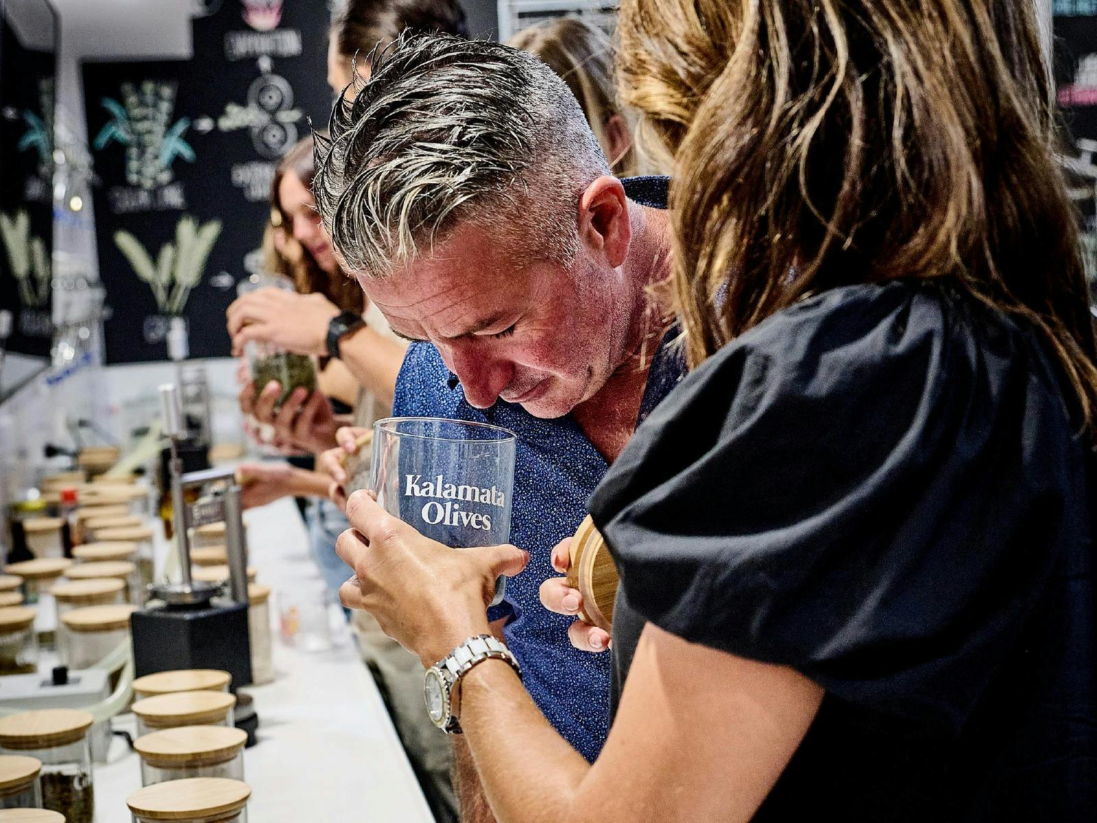 중년 남성이 몸을 굽혀 말린 식물 한 병의 깊은 냄새를 맡습니다.