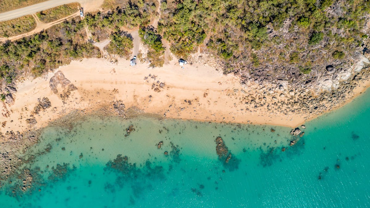 Aerial view of a small patch of sandy hydeaway bay beach with calm crystal clear waters