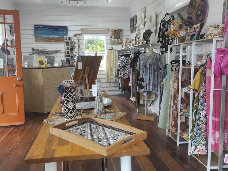 Display showing locally handmade clothing, home decor, art, and jewellery in front room of Gallery