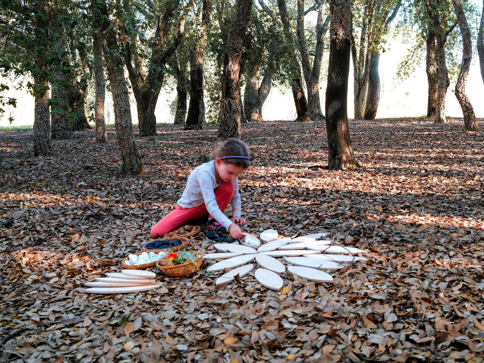 Girl sitting amongst fallen autumn leaves in Cork oak forest doing craft
