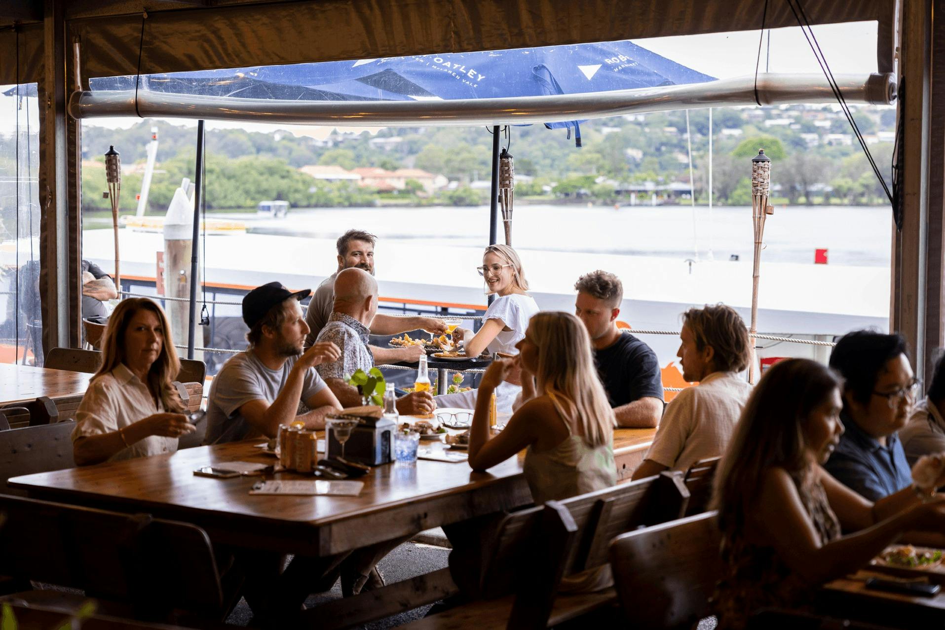 Family and friends enjoy a meal together overlooking the Tweed River at The Oyster Shed