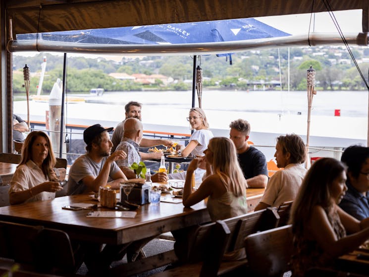 Family and friends enjoy a meal together overlooking the Tweed River at The Oyster Shed