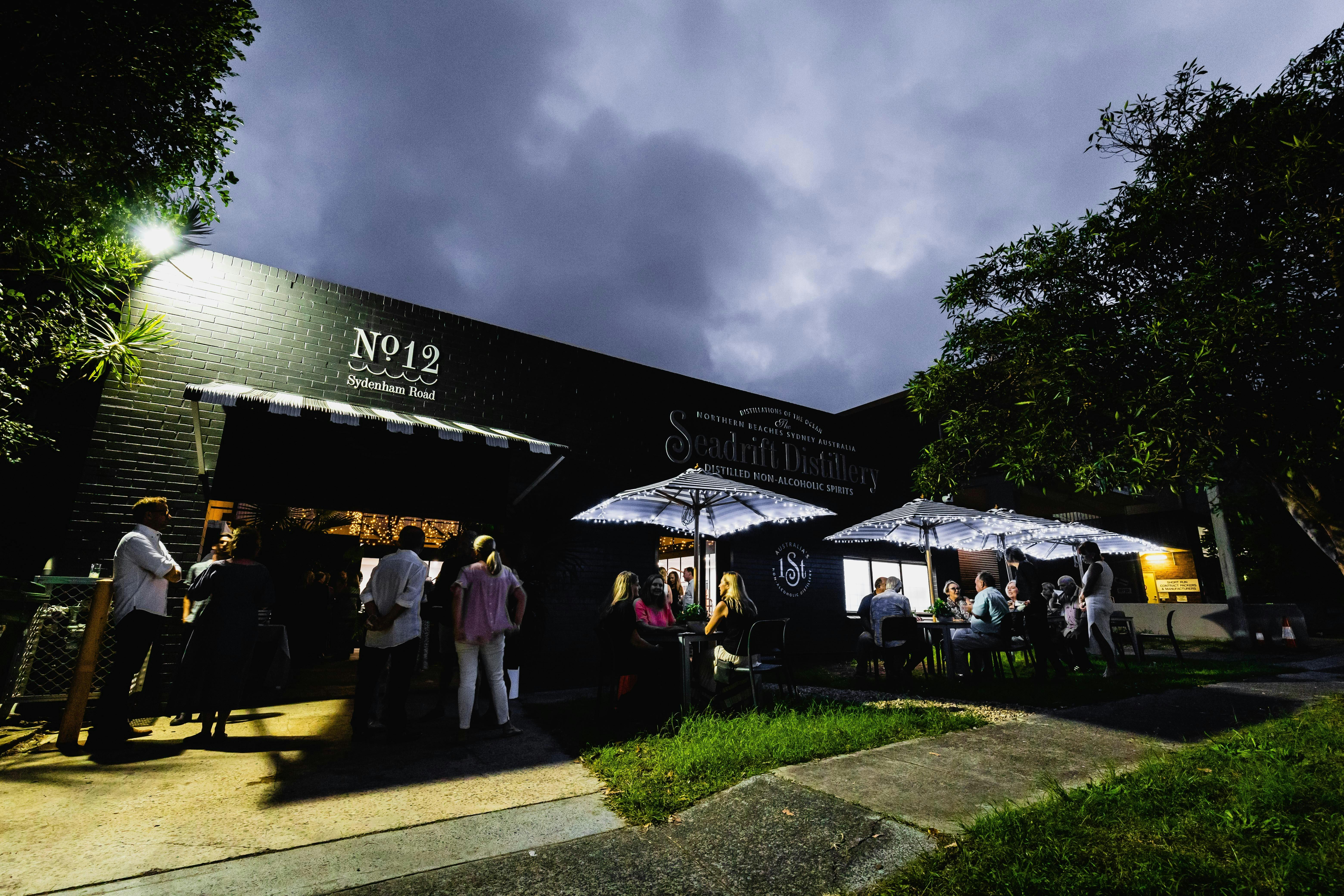photo of the front streetscape of Seadrift Distillery with people sitting on chairs  in the distance