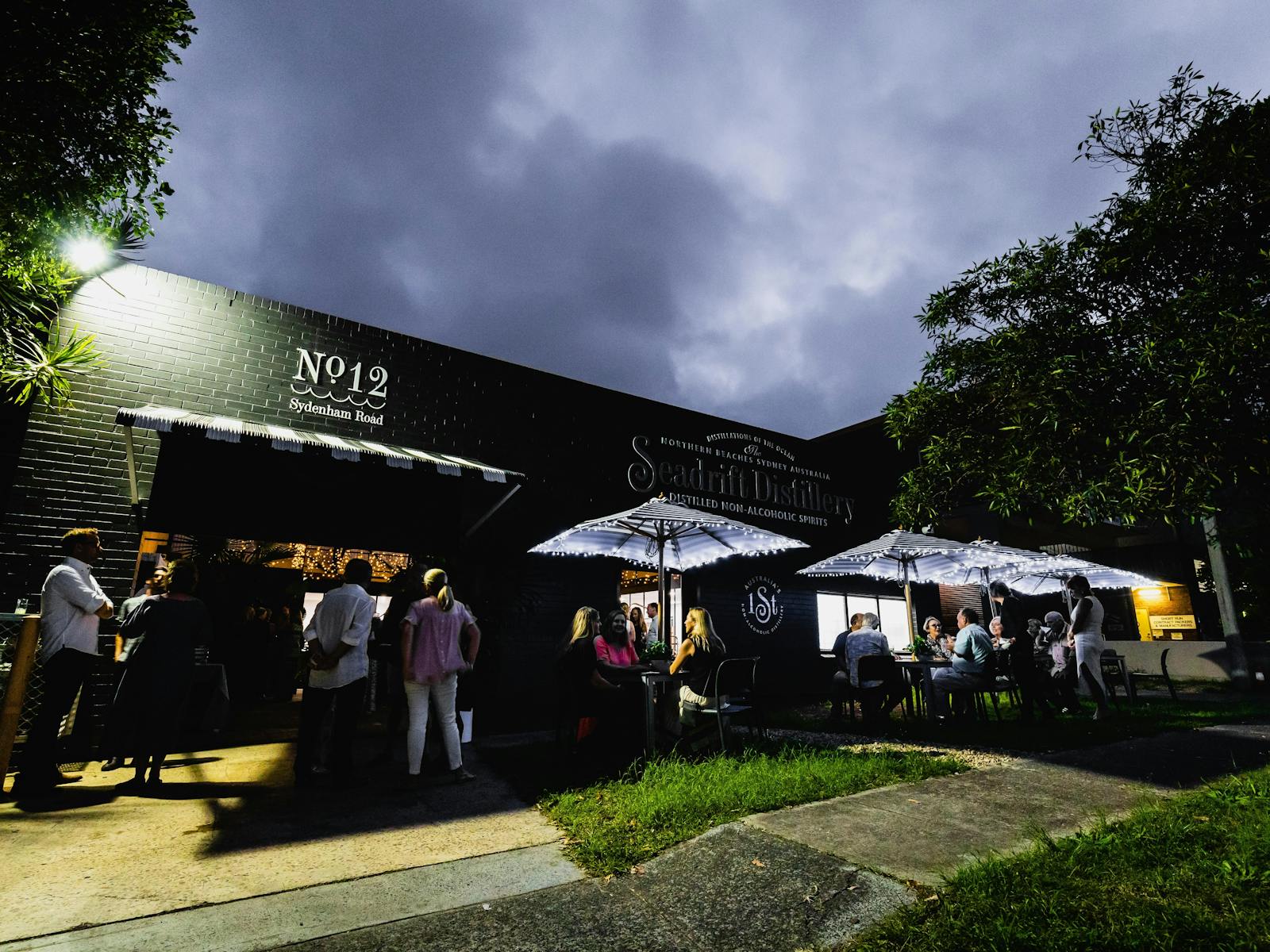 photo of the front streetscape of Seadrift Distillery with people sitting on chairs  in the distance