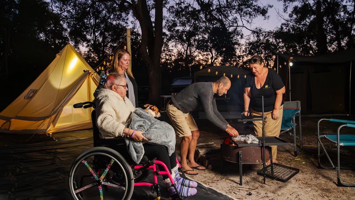 People around a camp fire cooking tea. Bell tent in the background