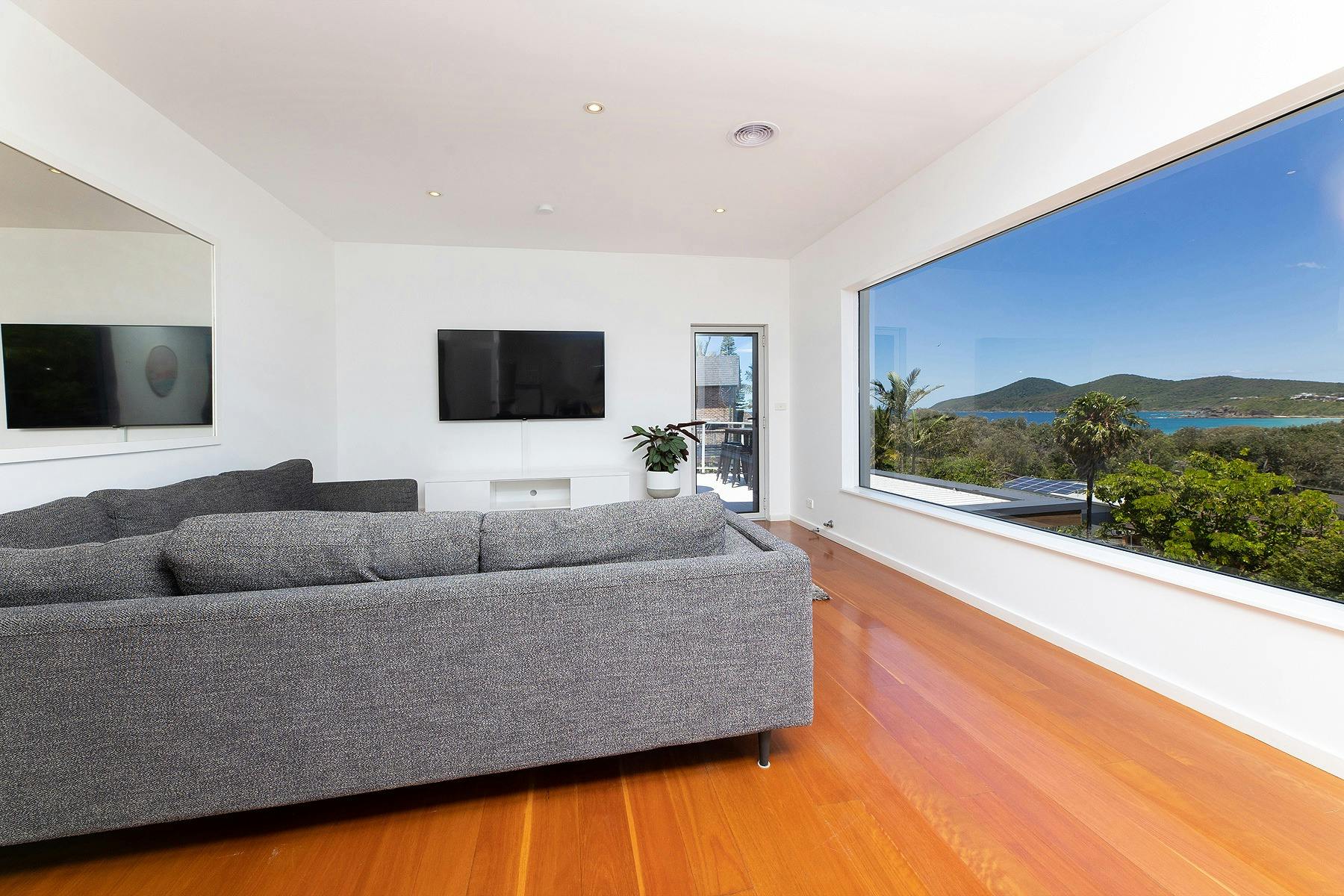 Loungeroom with spacious lounge, TV and panoramic views of the coastline