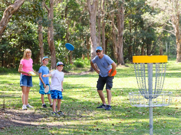 Family watching child play Disc Golf