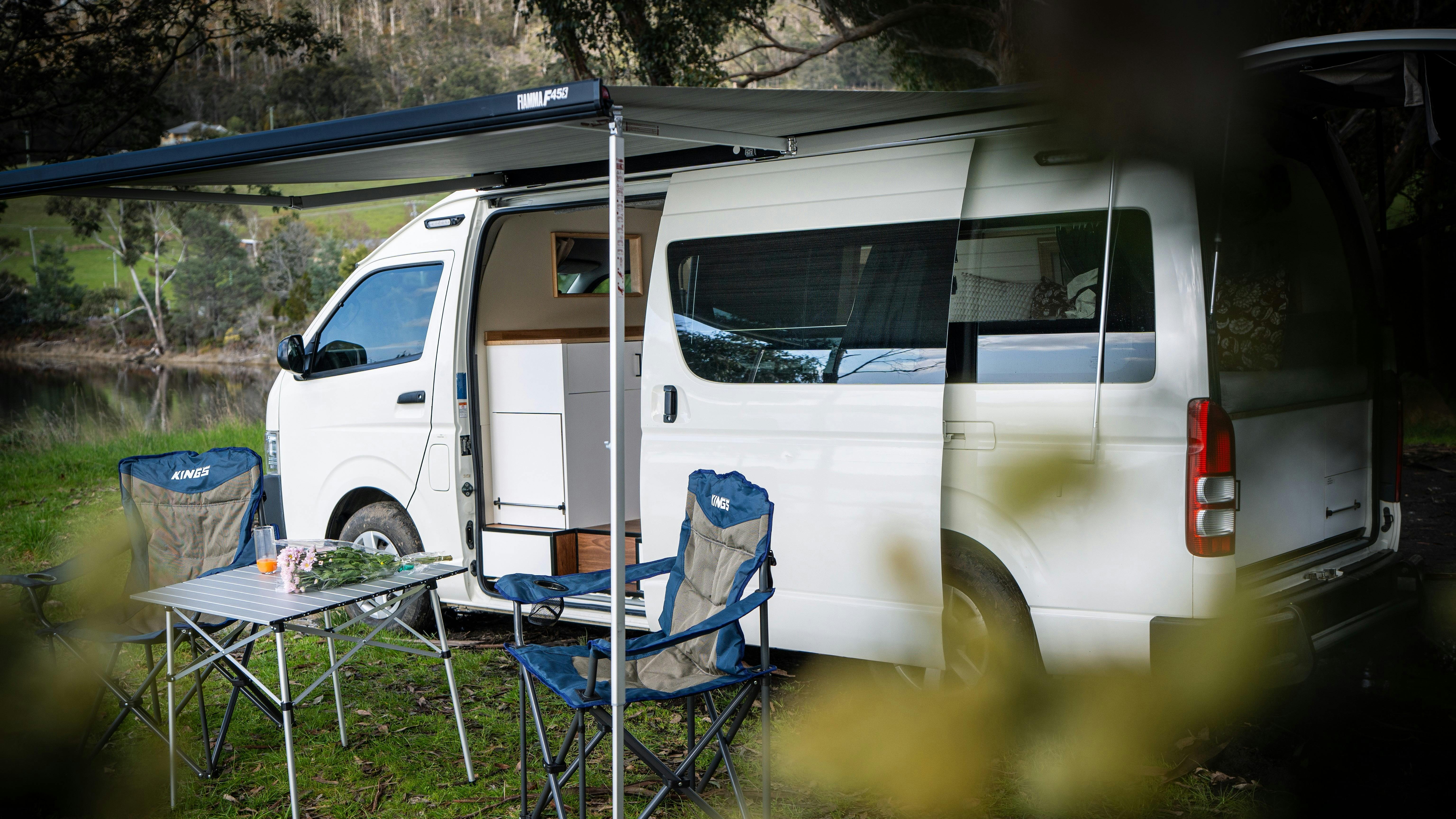 Manali campervan exterior with awning, camping chairs and table inviting Tasmanian nature escape.