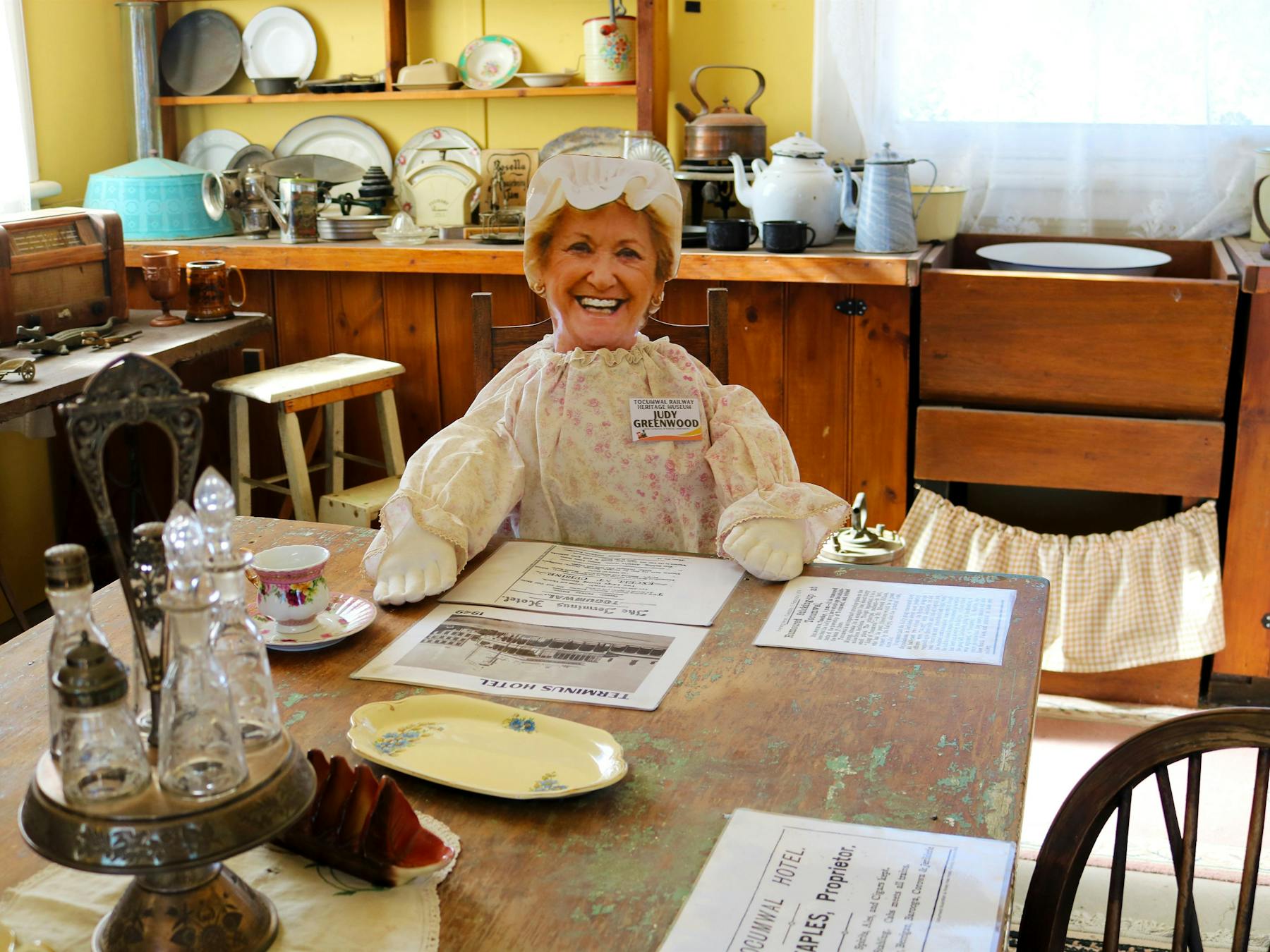 Museum interior, featuring a set table and dressed mannequin seated at table.