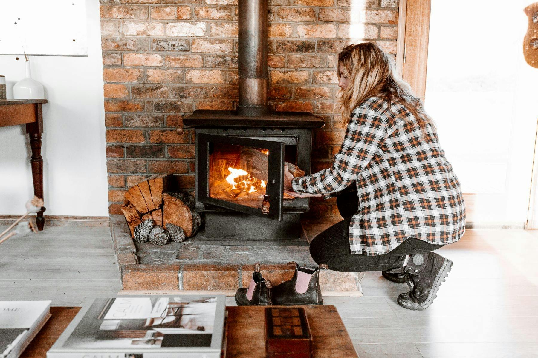 woman placing wood into wood fire heater