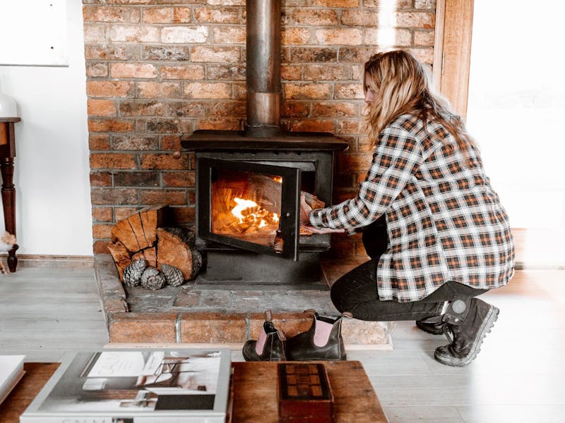 woman placing wood into wood fire heater