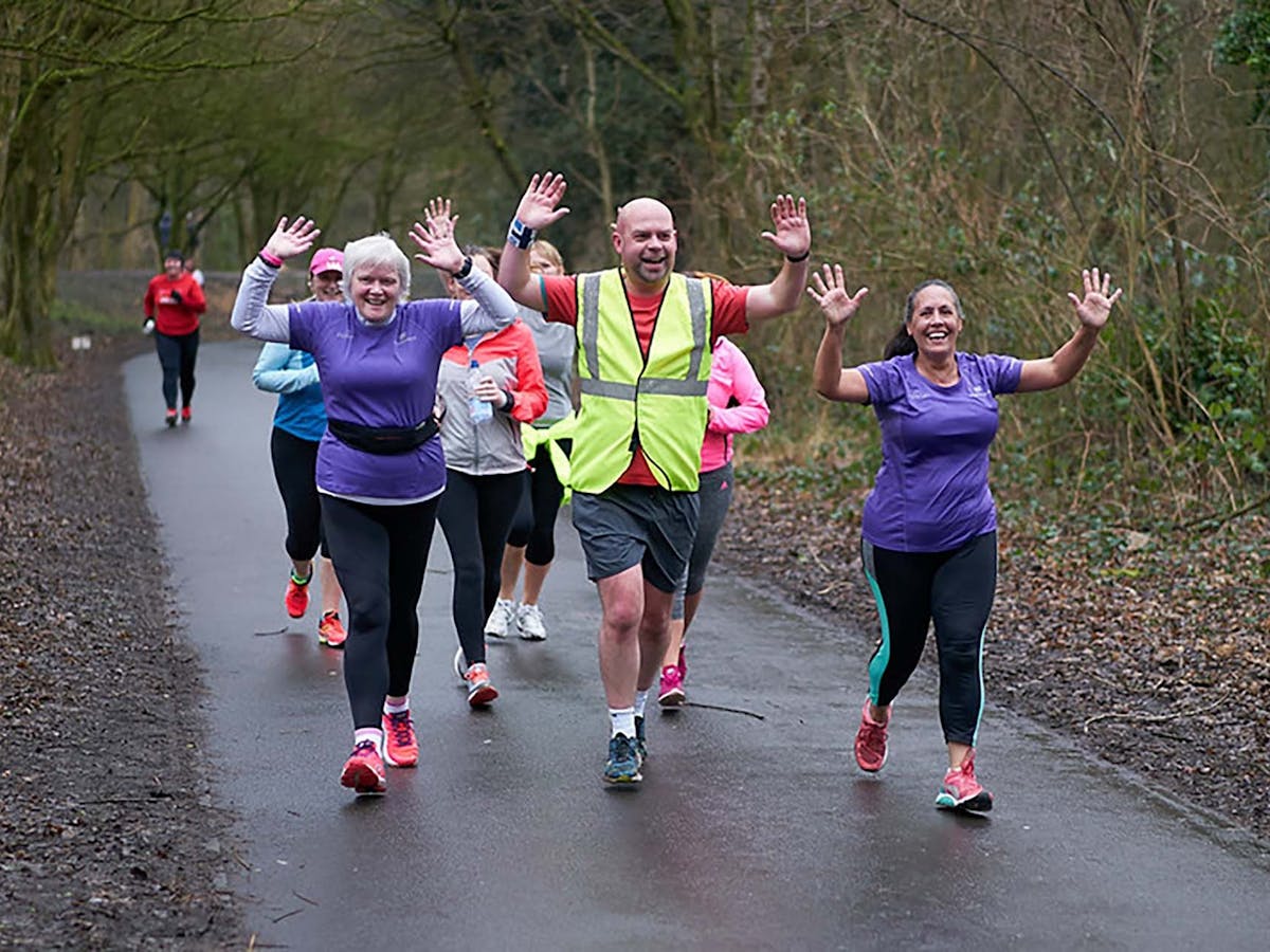 People with hands up running in woods