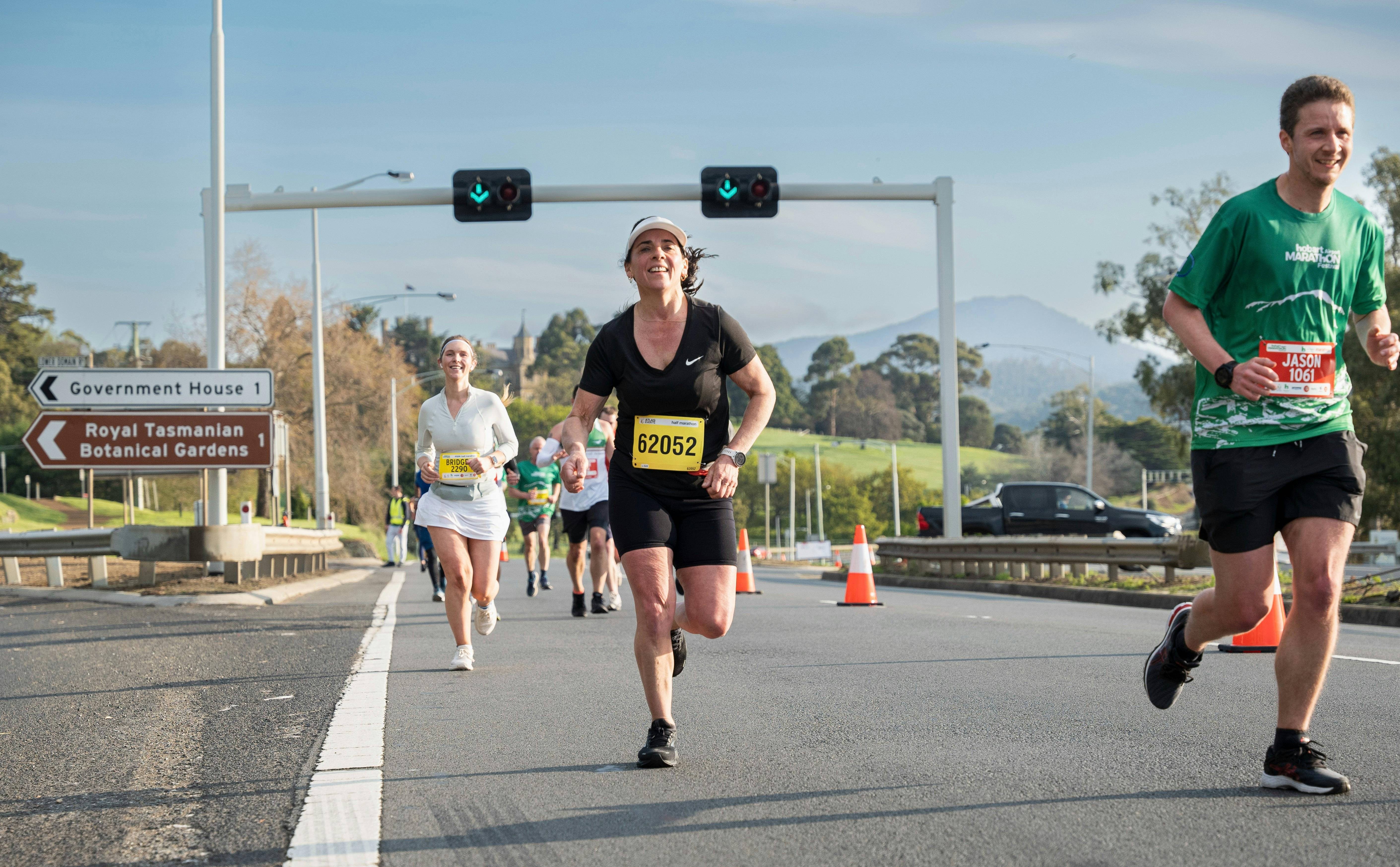 Runners running along the road with traffic lights behind them
