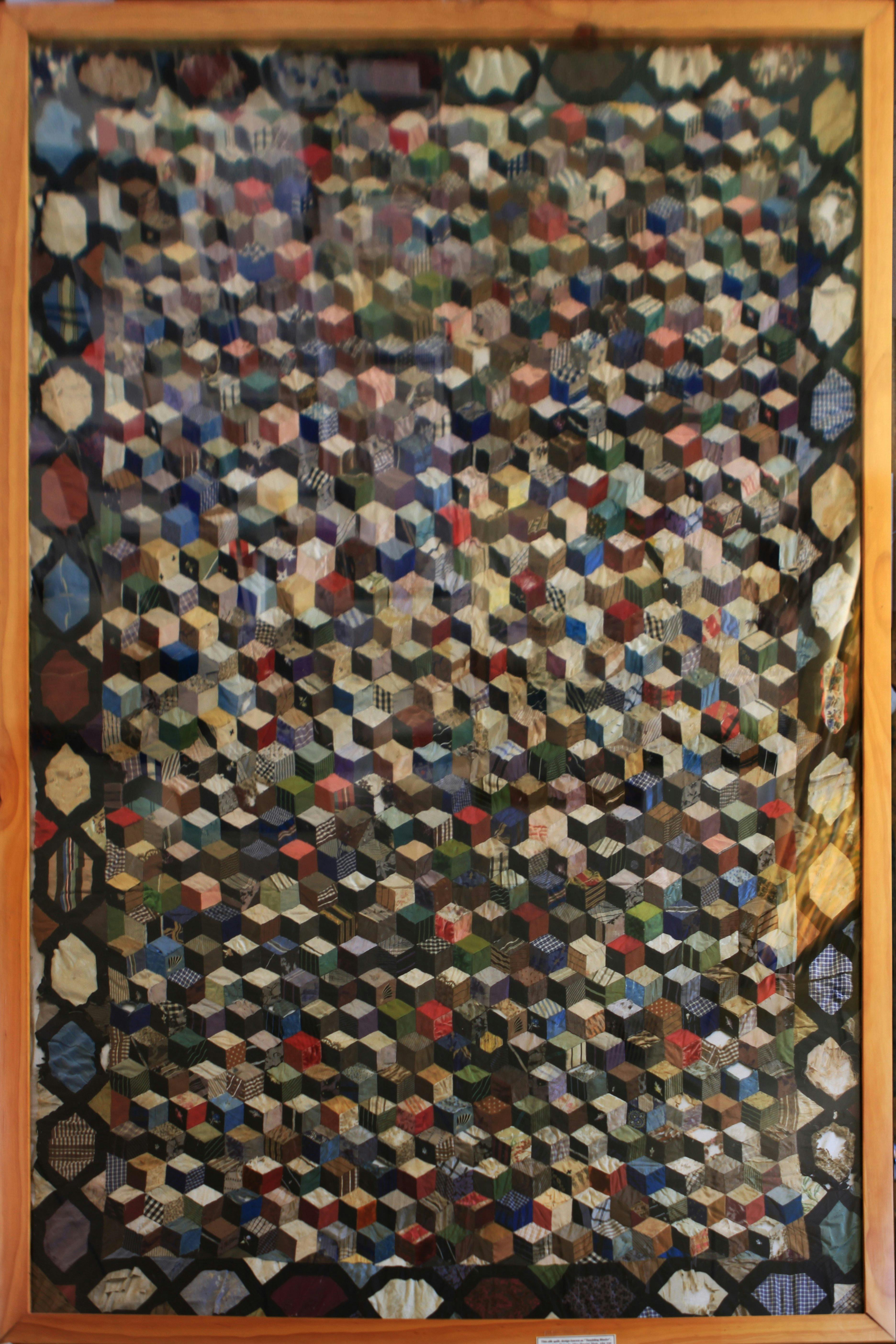 A colourful silky quilt made from the scraps of a household. It is in the tumbling blocks pattern.
