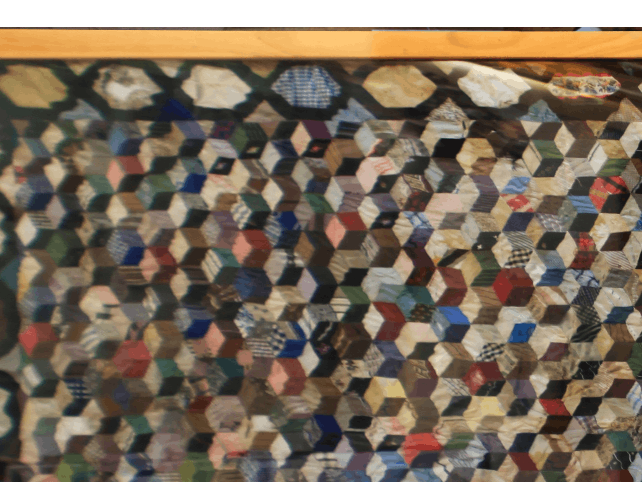A colourful silky quilt made from the scraps of a household. It is in the tumbling blocks pattern.
